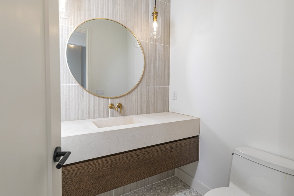 Powder room with a floating vanity and round mirror