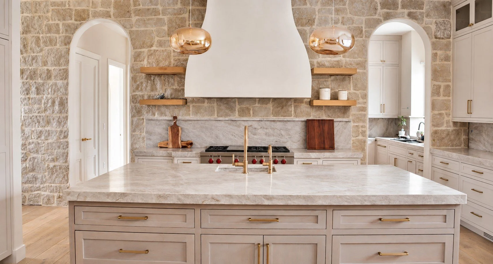 Prentice kitchen with a stone island, warm wood cabinetry and sculptural pendant lighting.