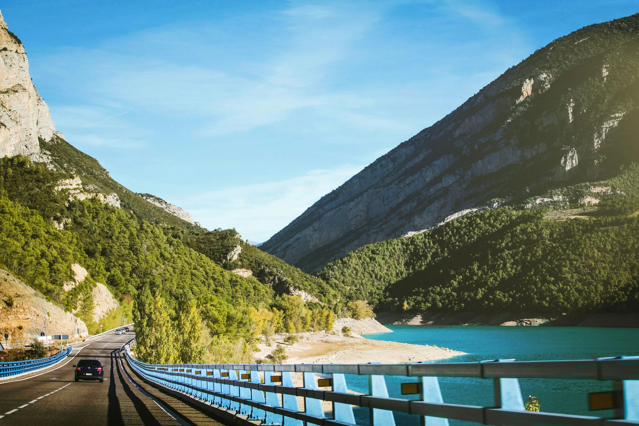 Road curving through a green mountain valley beside a reservoir in Spain
