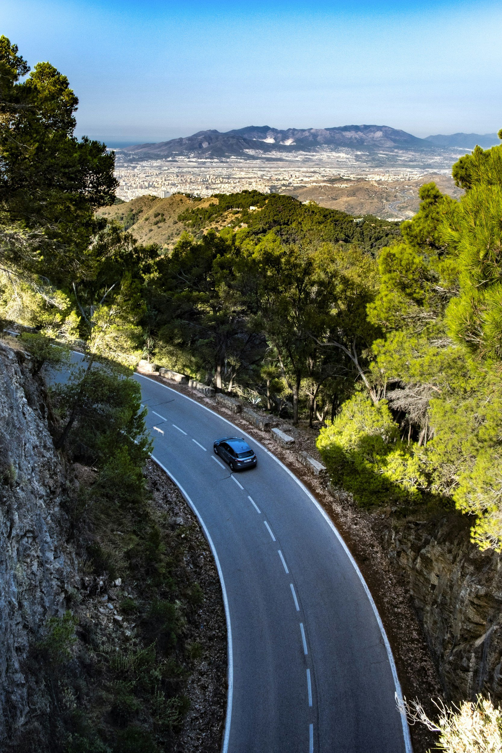Mountain road descending towards a Spanish coastal town