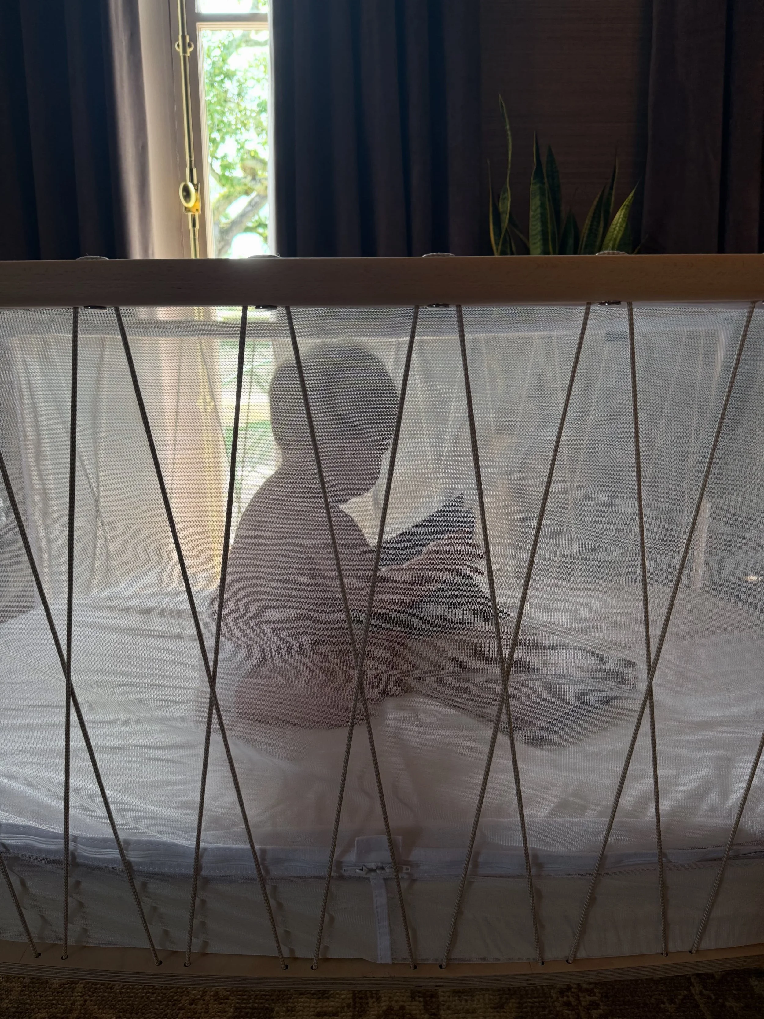A baby plays in a playpen after his mother had a virtual sleep support session with Rachel Bernhard.