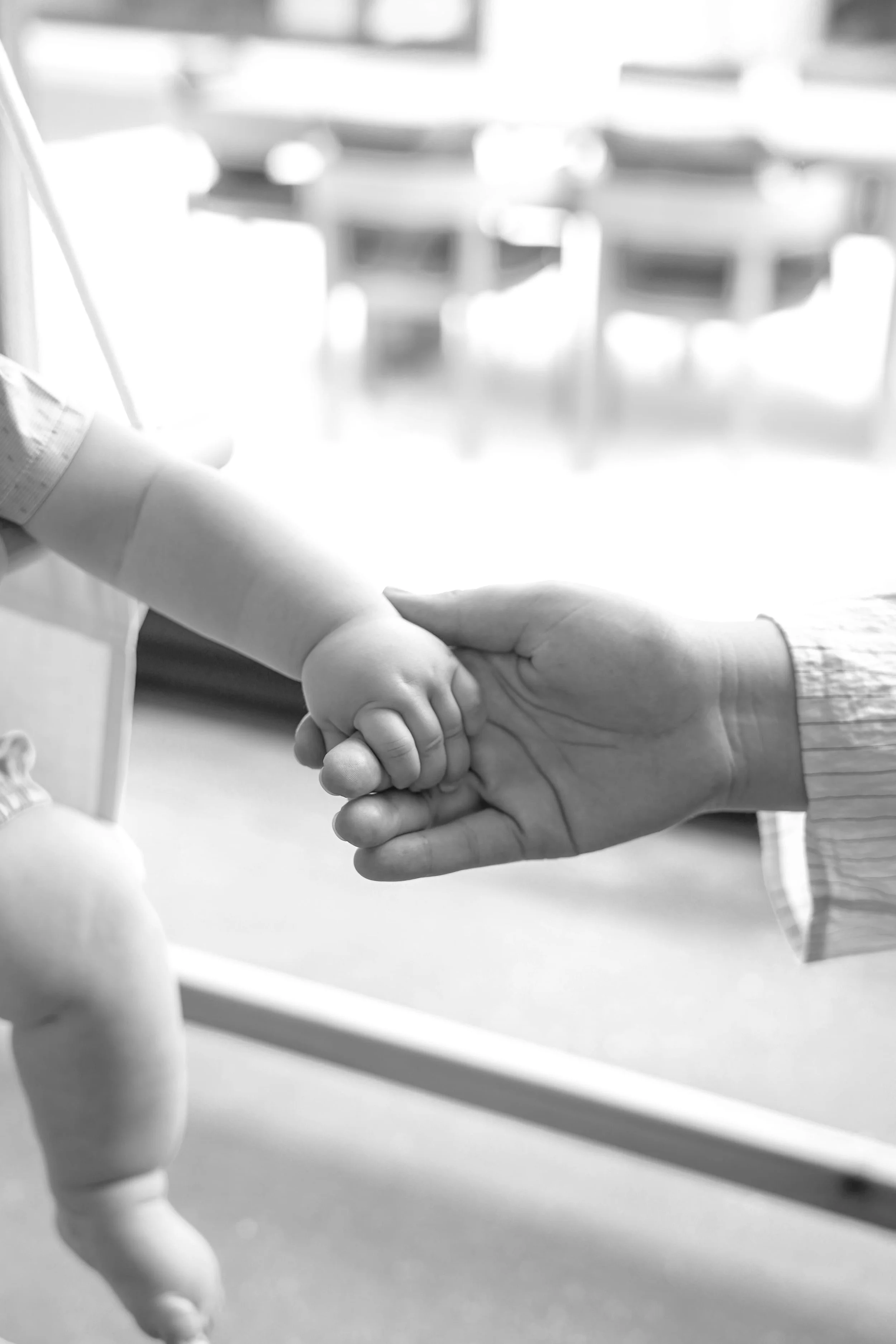 A mother, who is a member of The Postpartum Village and receives maternal and postpartum mental health support, holds hands with her baby.