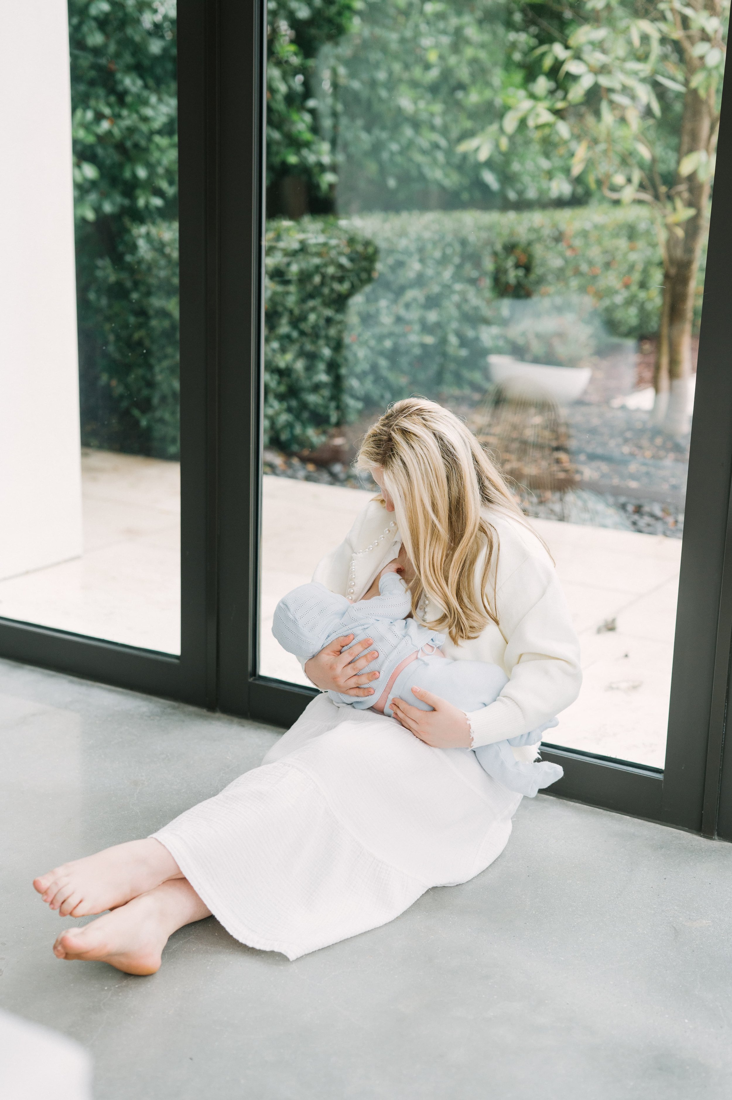 Rachel Bernhard, founder of the virtual motherhood circle The Postpartum Village, sits on the floor and breastfeeds her child.