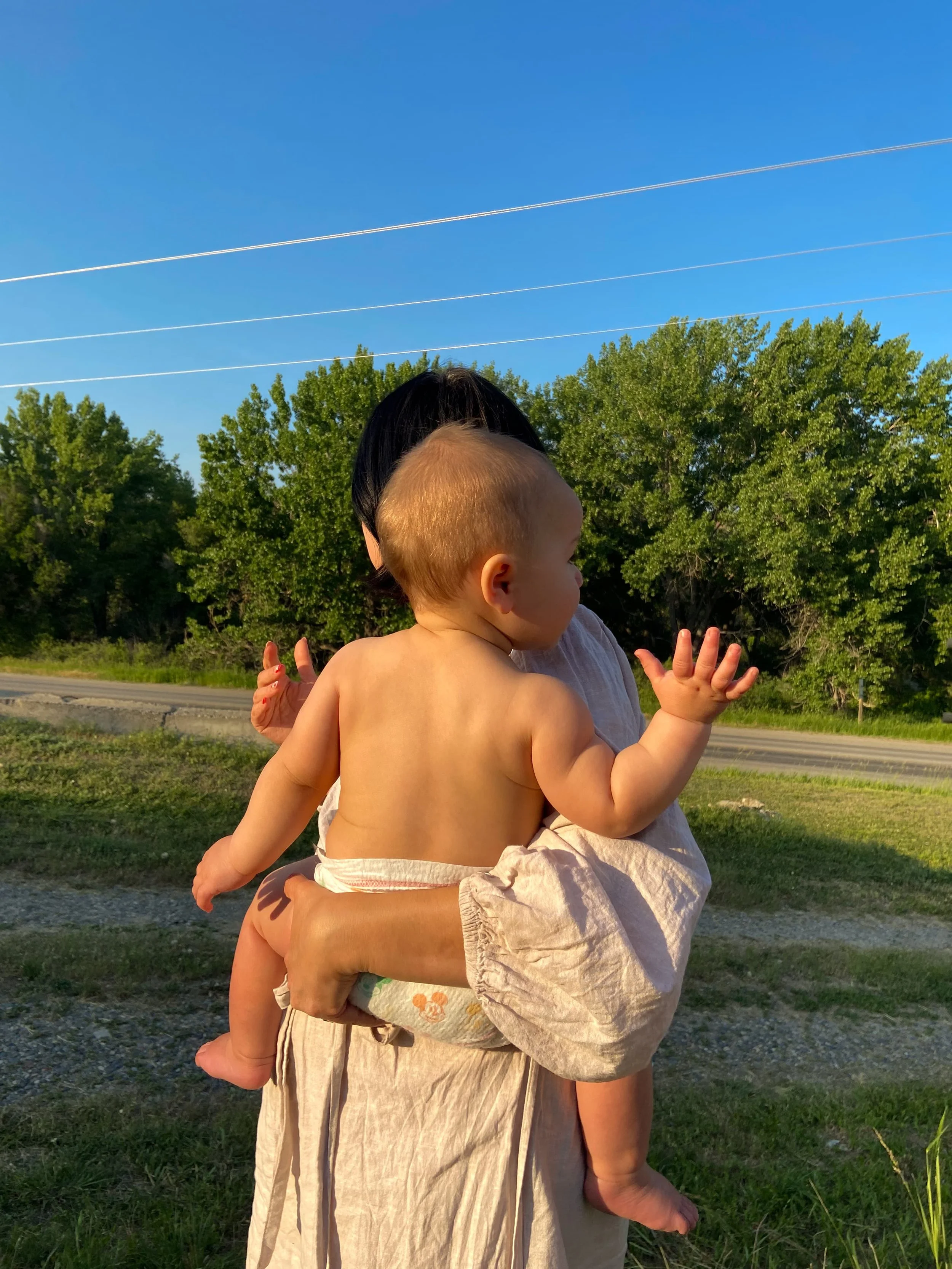 A mother benefitting from breastfeeding and newborn sleep support in The Postpartum Village with Rachel Bernhard hols her baby outside.