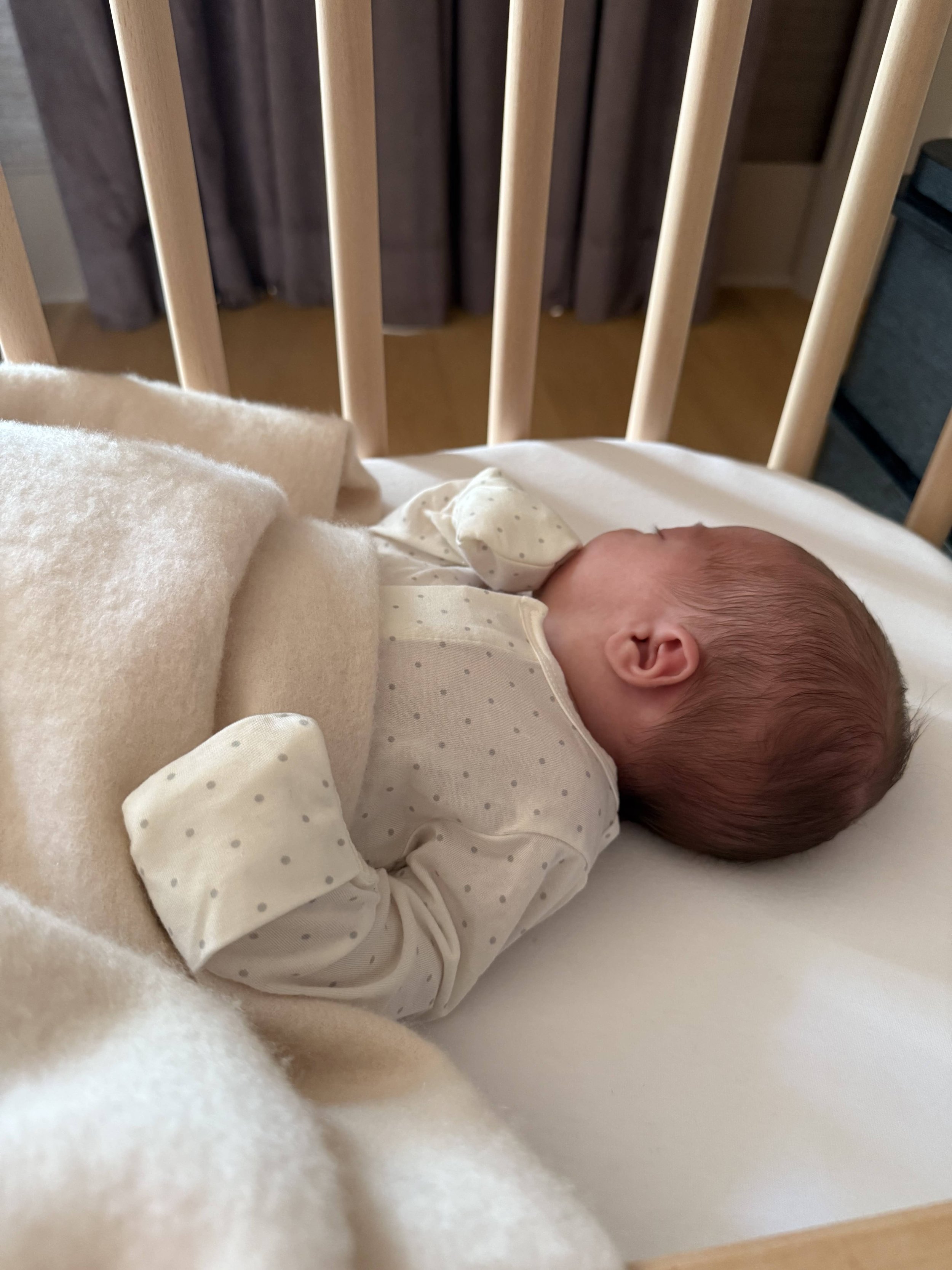Newborn sleeping peacefully in a crib during a daytime nap.