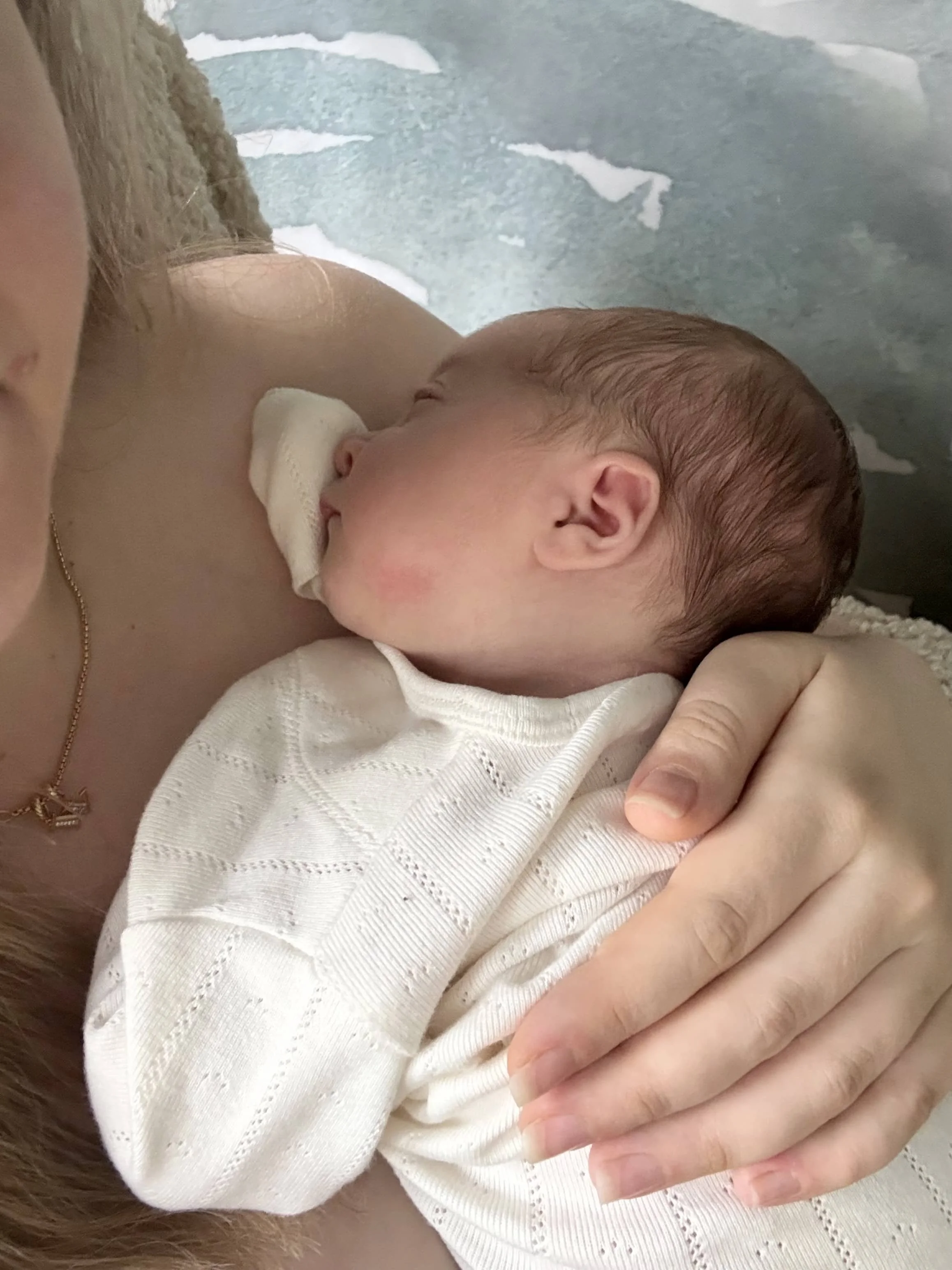 Rachel Bernhard holding a newborn during an in-home postpartum doula visit in New York City.