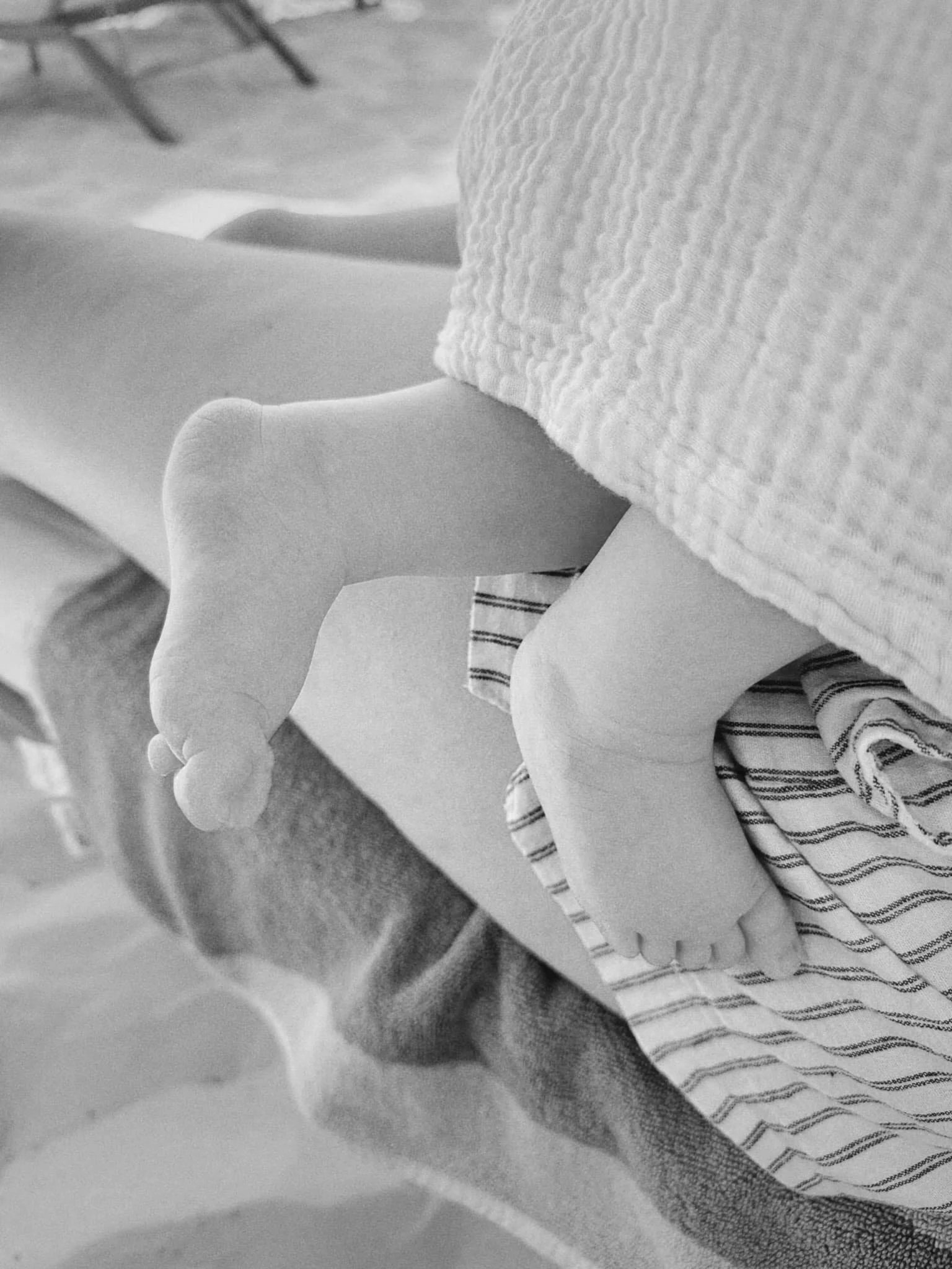 Close up image of newborn baby toes while sleeping on birth doula's lap.