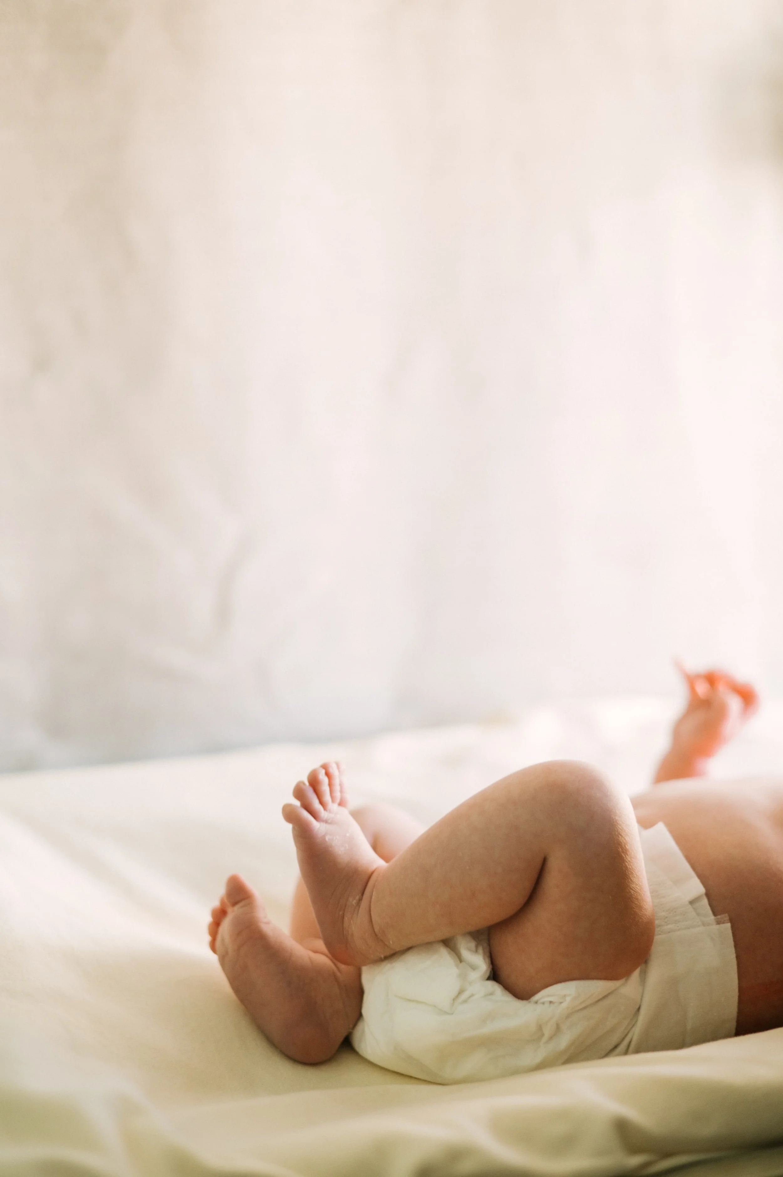 A mother who is mindful of her infant's mental health and responsive sleep support, lays her baby on a changing station with a diaper on.