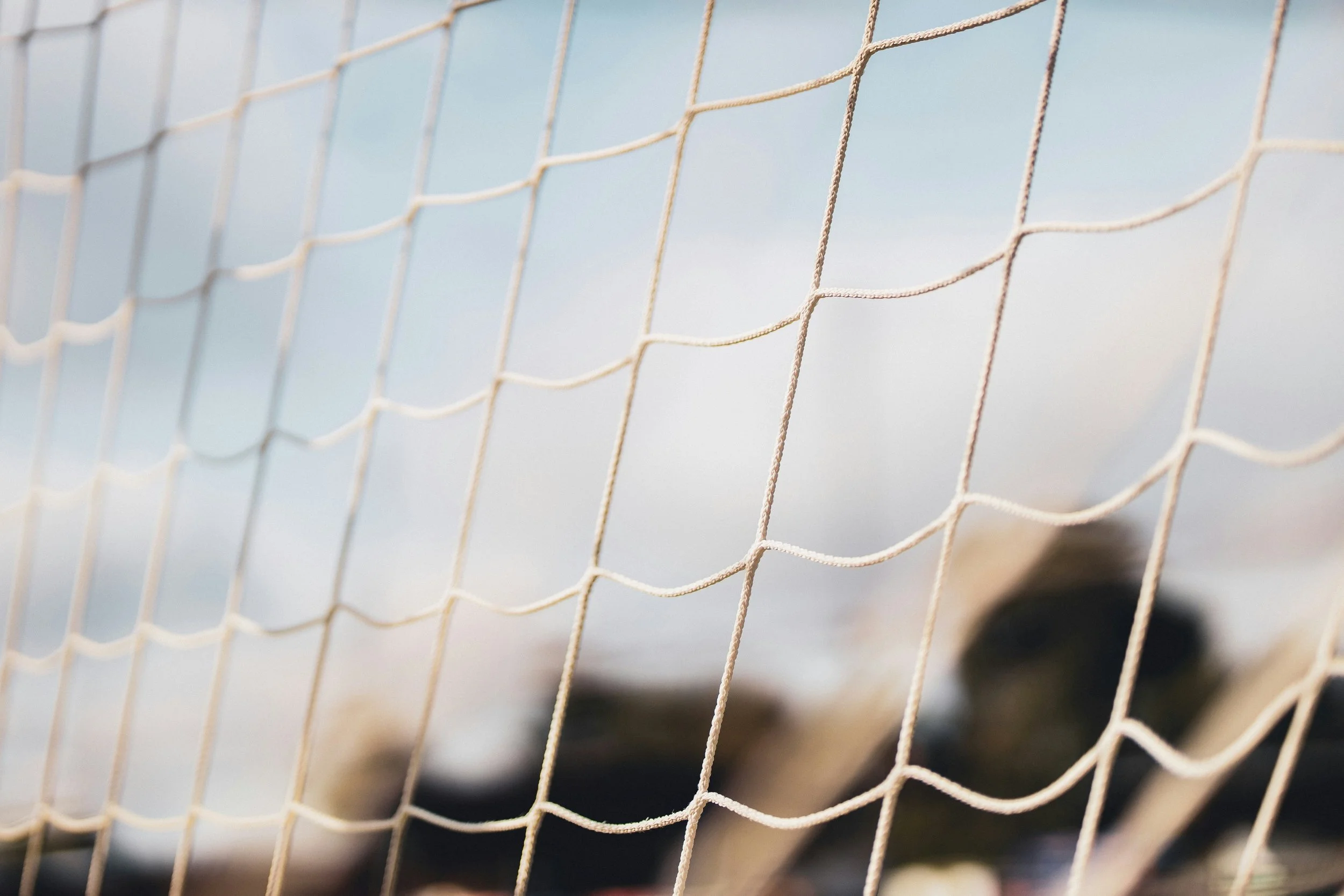 Close-up of a beige sports net with a clear blue sky in the background.