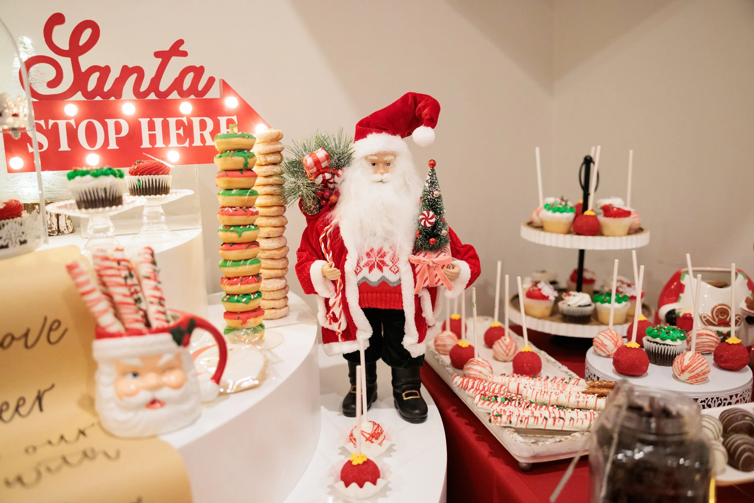 Christmas dessert display with a Santa figure, cupcakes, cookies, candy canes, and holiday decorations.
