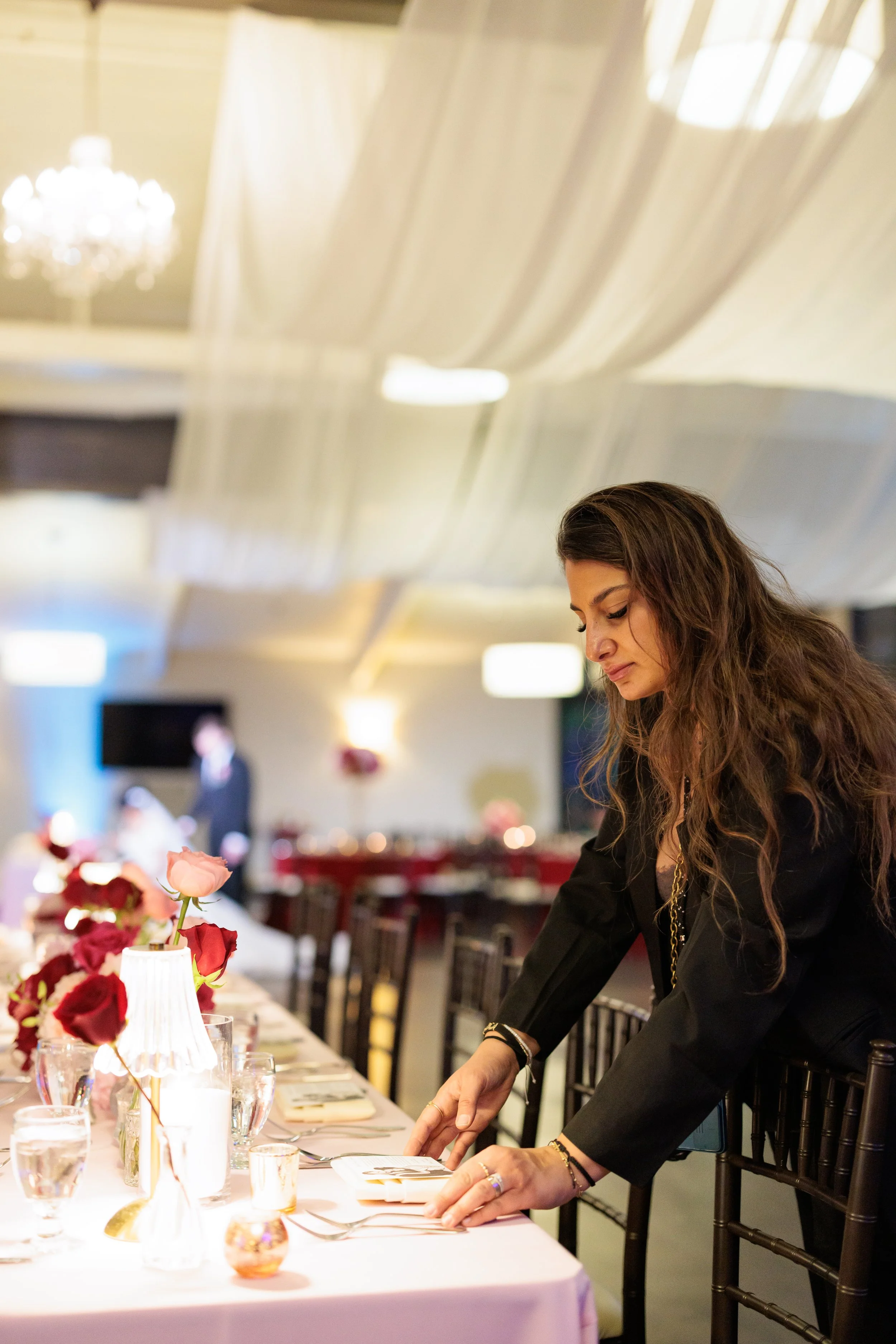 woman setting table at a formal event or wedding reception with decorated table and floral arrangements