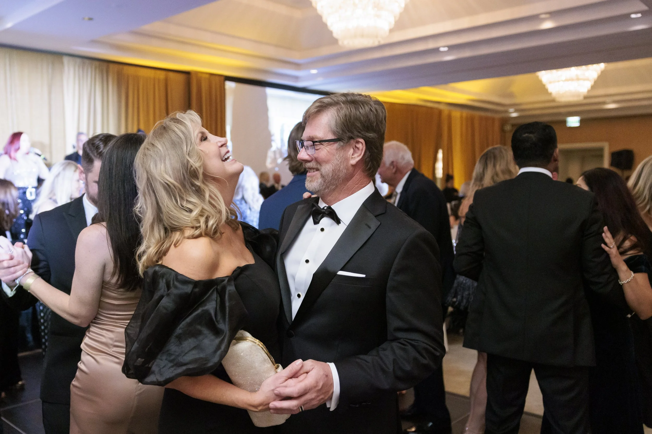 Man and woman dancing at a formal event with others in the background