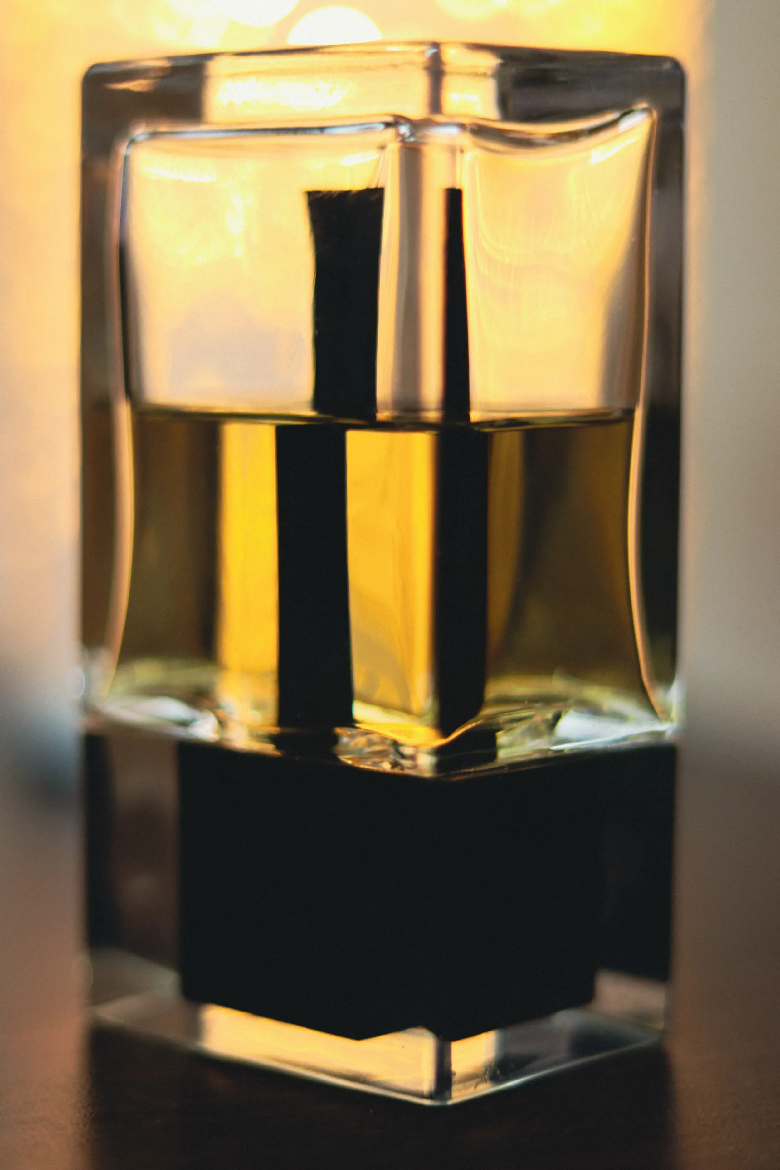 Square glass bottle with golden liquid and black base