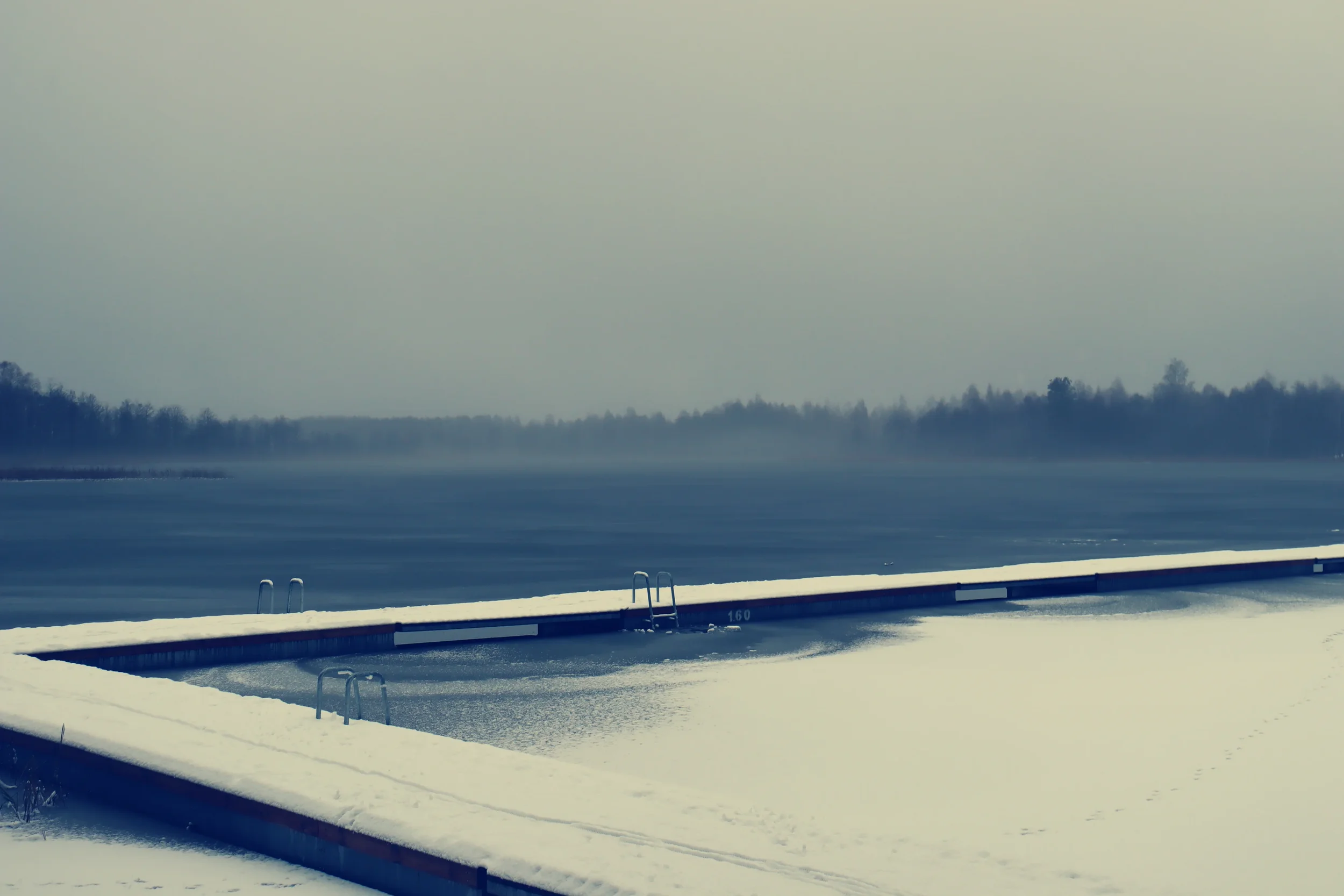 Winter lake with foggy forest in the background