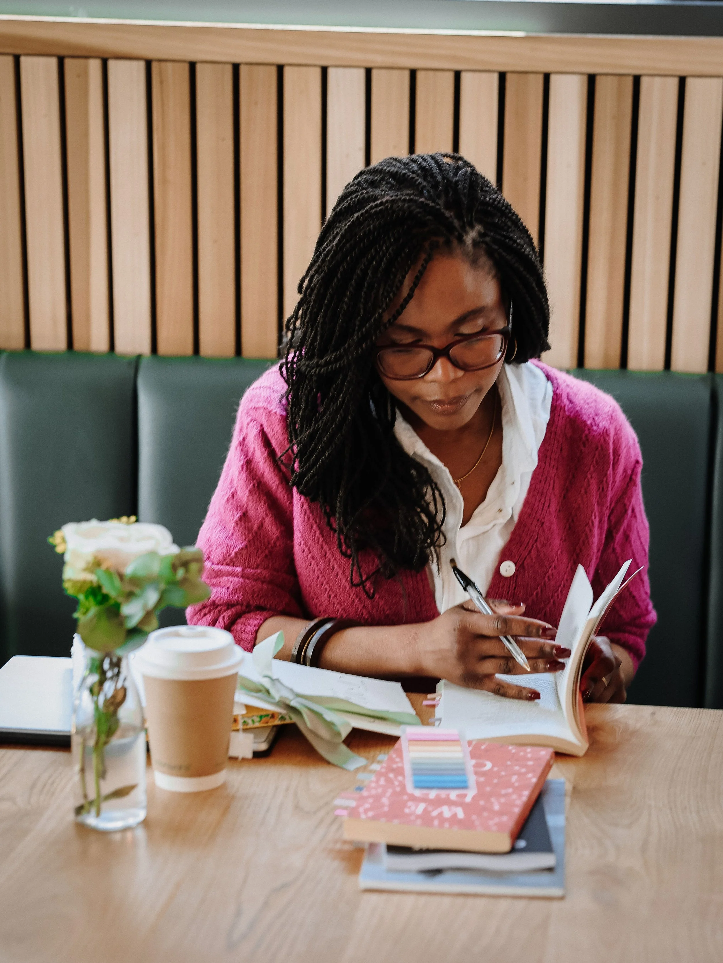 A wedding celebrant sits in a cafe preparing  notes and finding readings for a couple