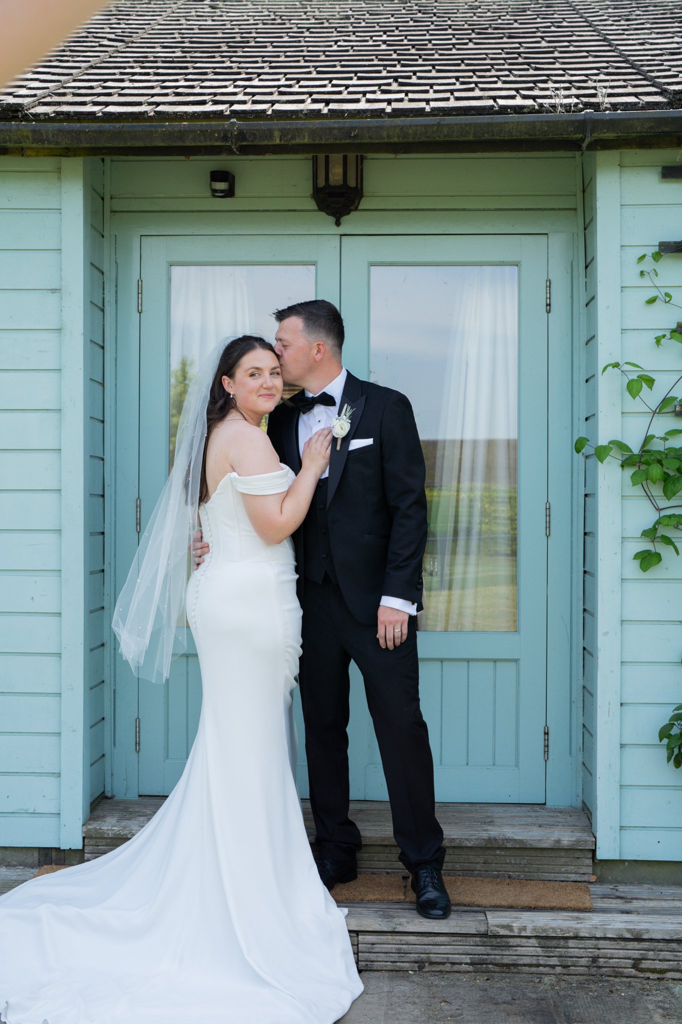 a couple on their wedding day in front of a blue cladded building