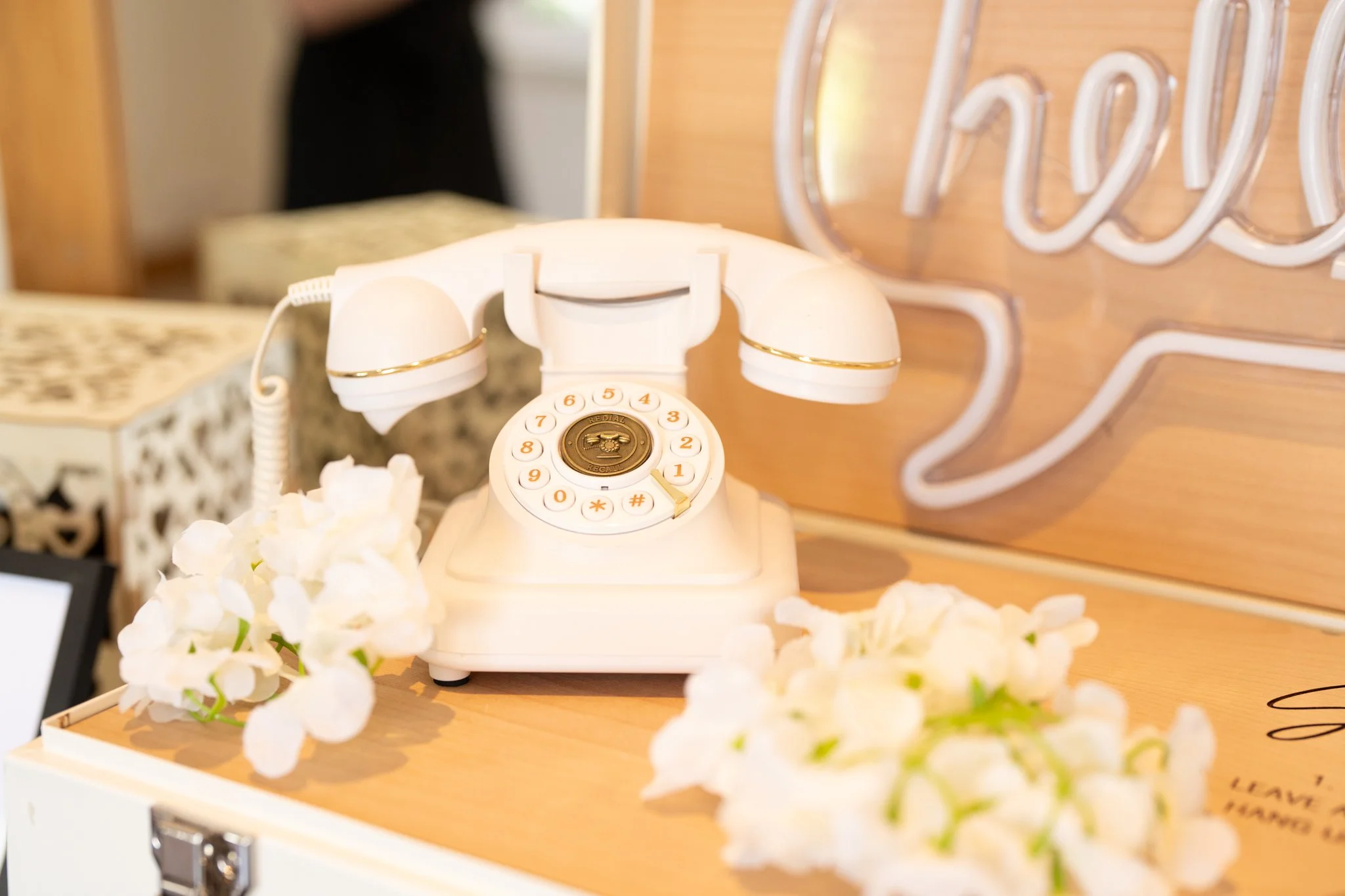 A vintage white rotary telephone resting on a table surrounded by white flowers. Anne Wills Photography Maidens barn Essex