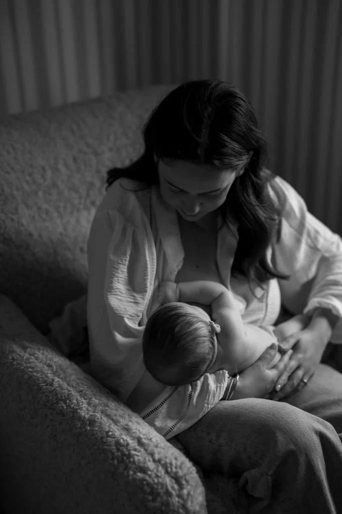 A woman breastfeeding a young child on a couch in a cozy room.