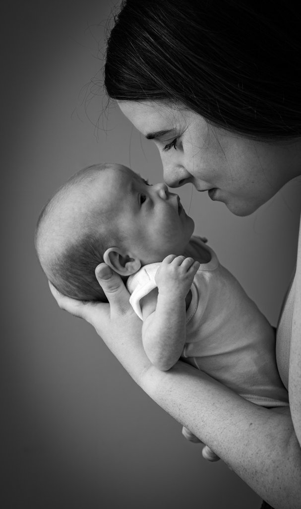 A woman holding a baby close, both touching foreheads, in a black and white photograph.