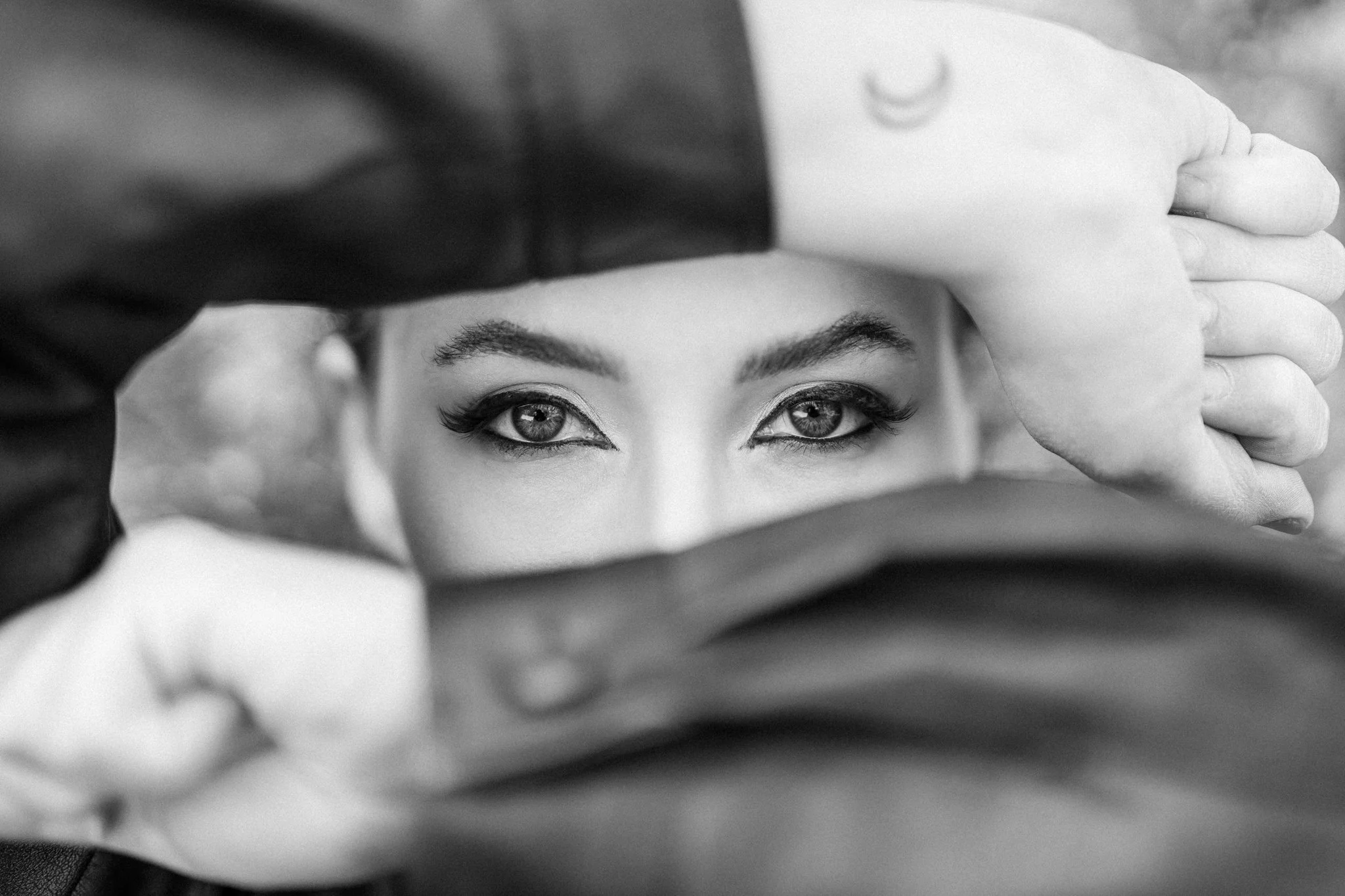 A woman with striking eyes looking through a mirror or glass, with her hand resting on her forehead. photographed in chelmsford, Essex. Anne Wills Photography 