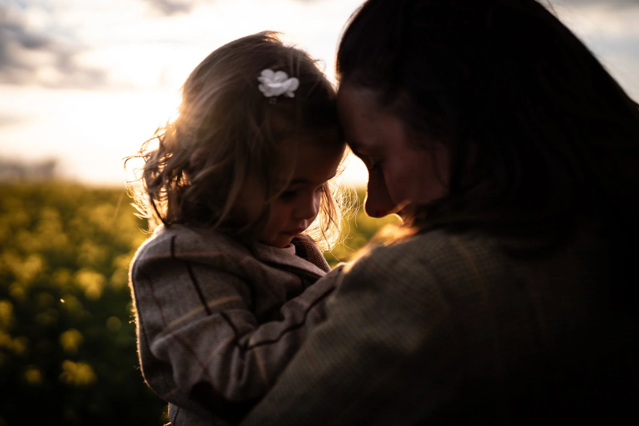 mum and daughter at sunset touching heads