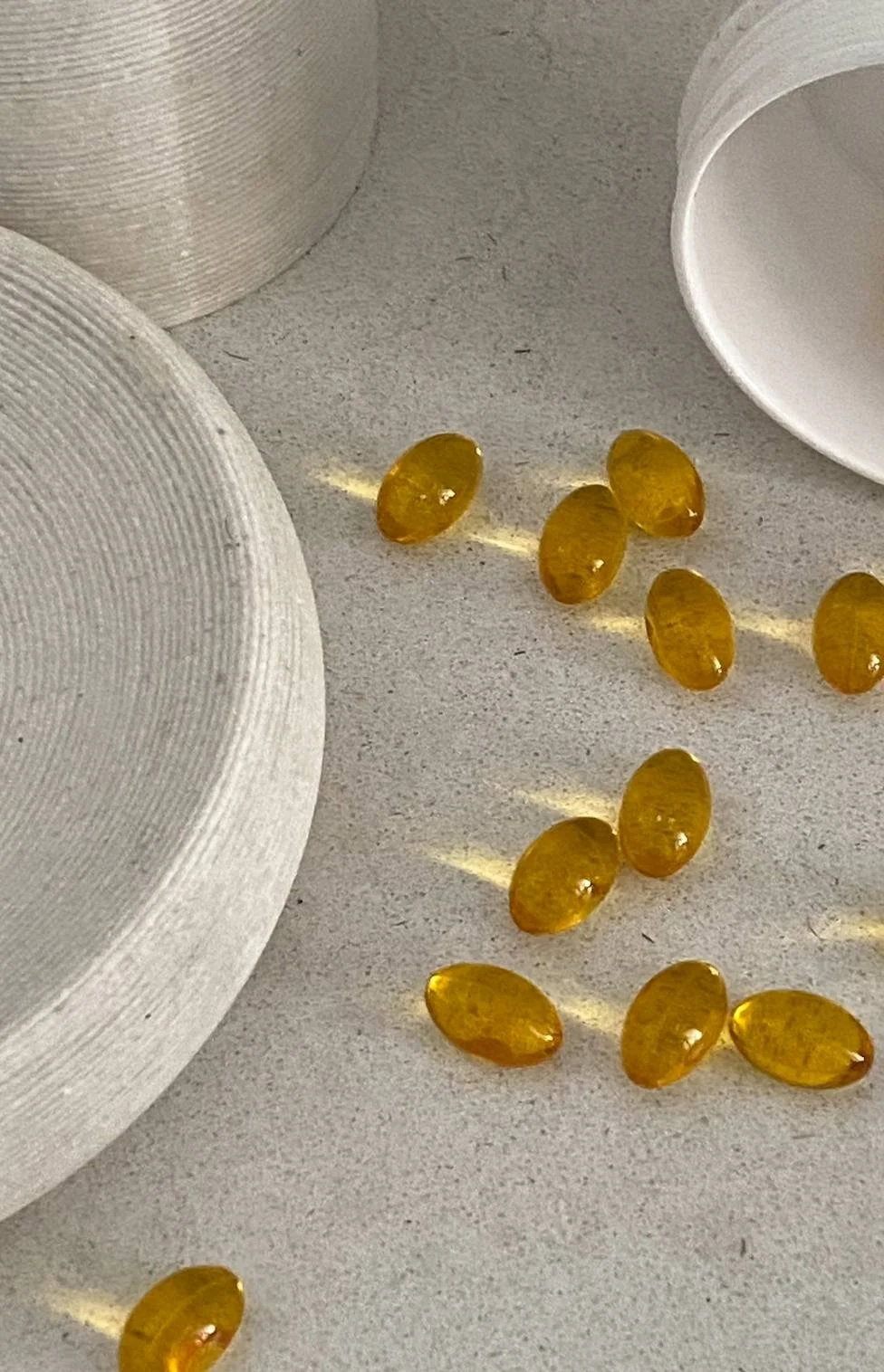 Yellow oval-shaped capsules scattered on a white surface with white cylindrical objects nearby.