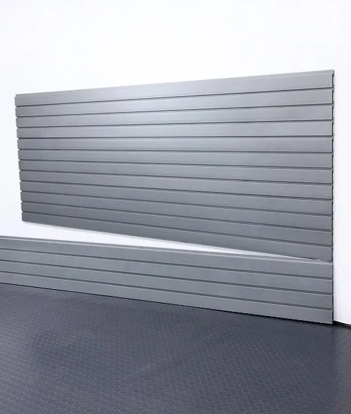A garage door that is halfway open, with a textured gray floor and white wall.