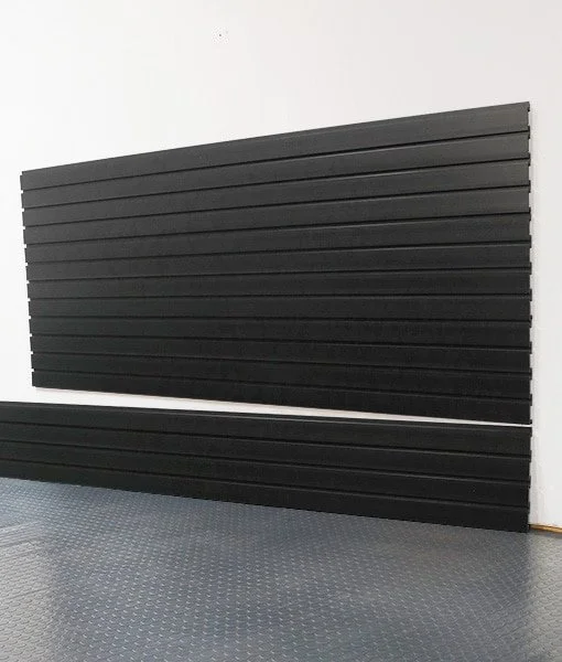 A large black felt letter board with rows of horizontal slats, leaning against a white wall on a gray textured floor.