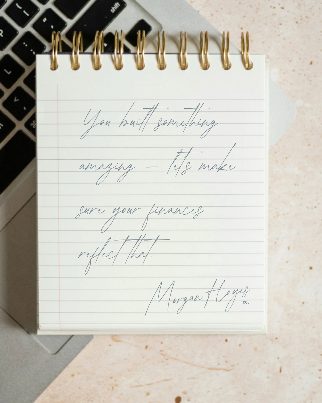 Notebook with handwritten motivational quote placed on a desk next to a laptop keyboard.