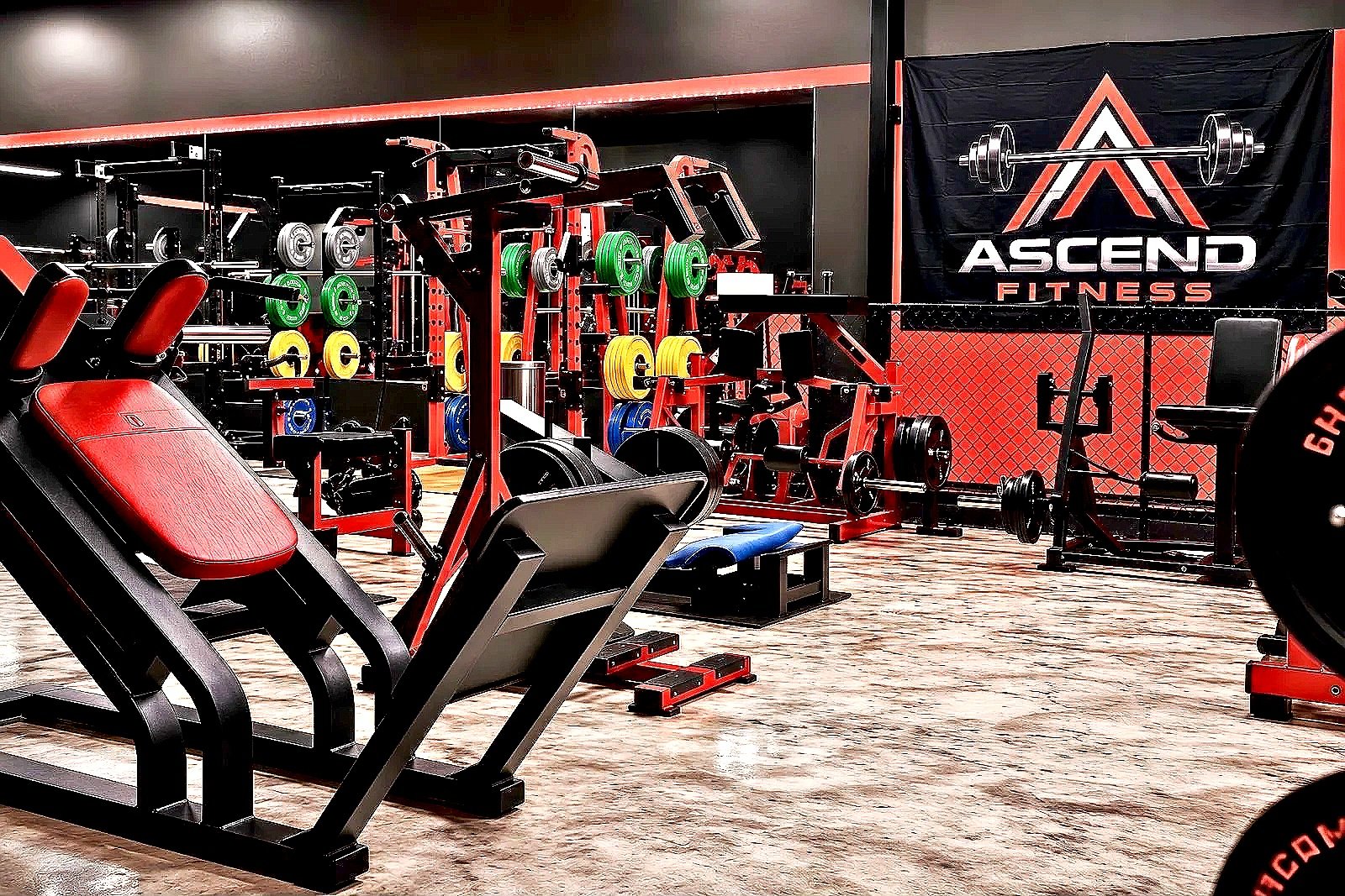 Interior of Ascend Fitness Cypress with various fitness equipment including weightlifting racks, weight plates, and a workout machine.