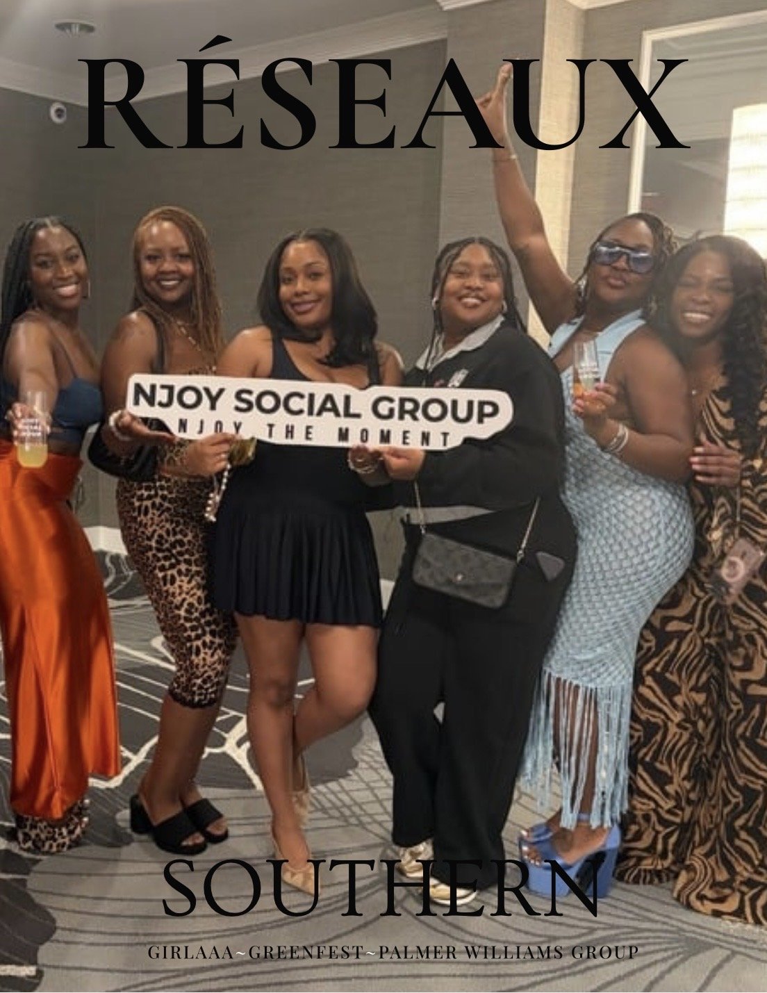 Group of seven women at a social gathering, holding a sign that says 'NJOY SOCIAL GROUP, NJOY THE MOMENT'. They are dressed stylishly, with some in patterned dresses and others in casual wear. The background shows an indoor venue with a carpeted floor and a wall with lighting.
