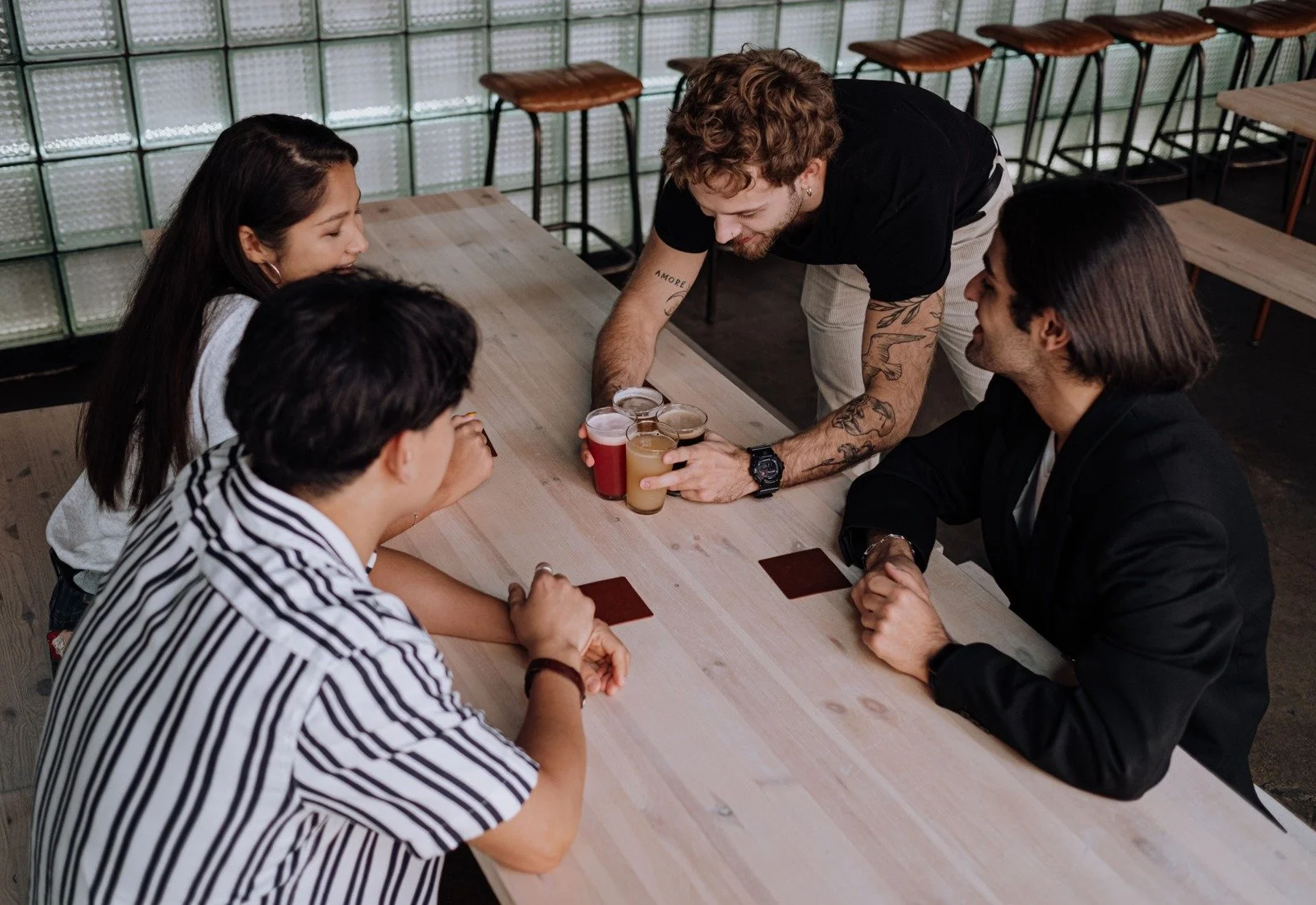 A server brings coffee to guests gathered around a café table.