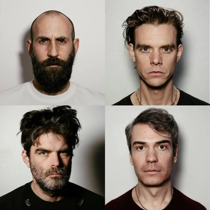 Four men with serious expressions, diverse hair and beard styles, in front of plain backgrounds.