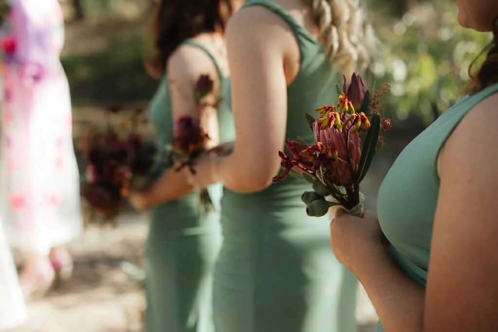 Women holding bouquets of flowers at an outdoor event.