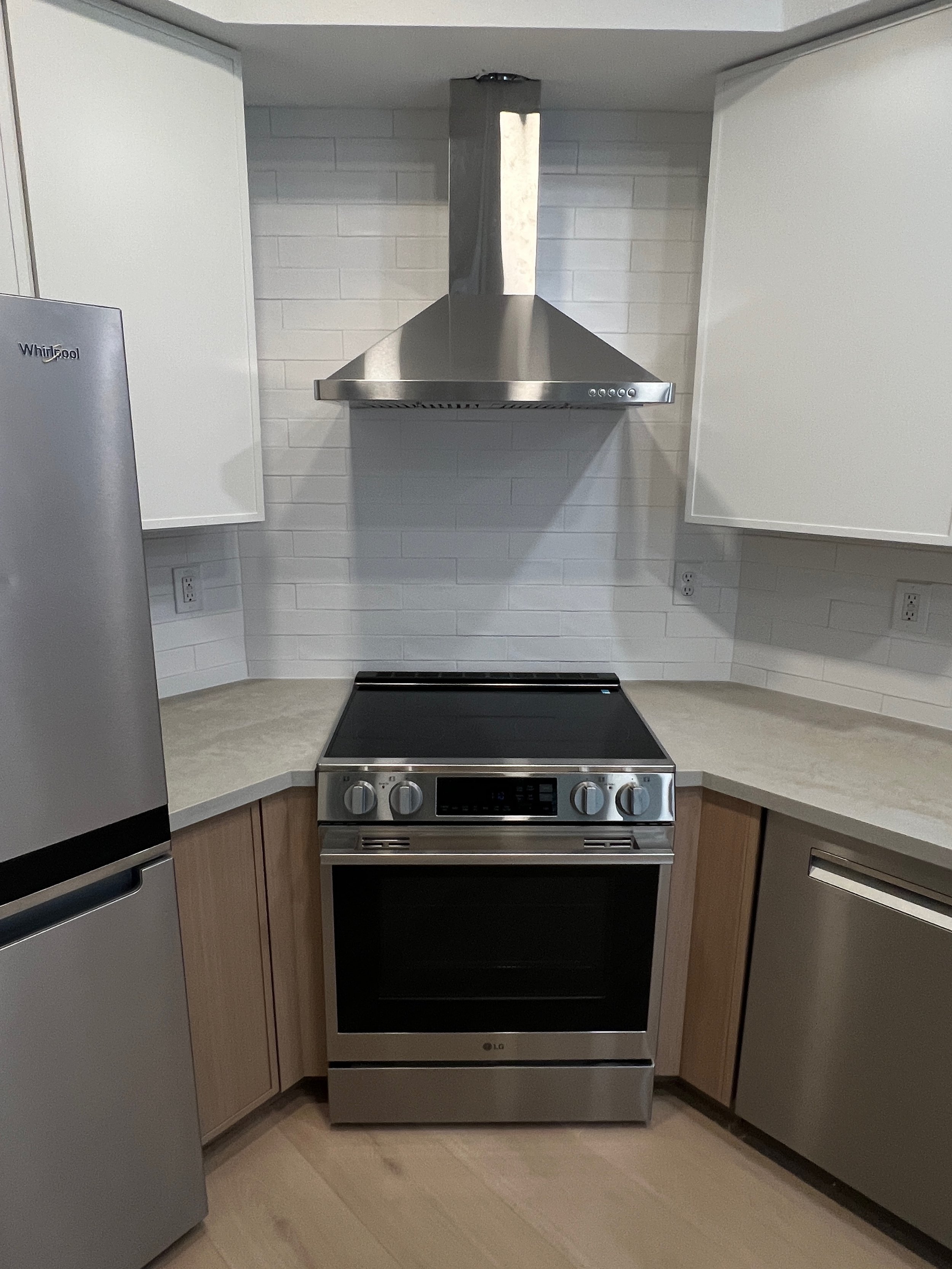 Modern kitchen with a stainless steel stove, white cabinetry, and a gray countertop.