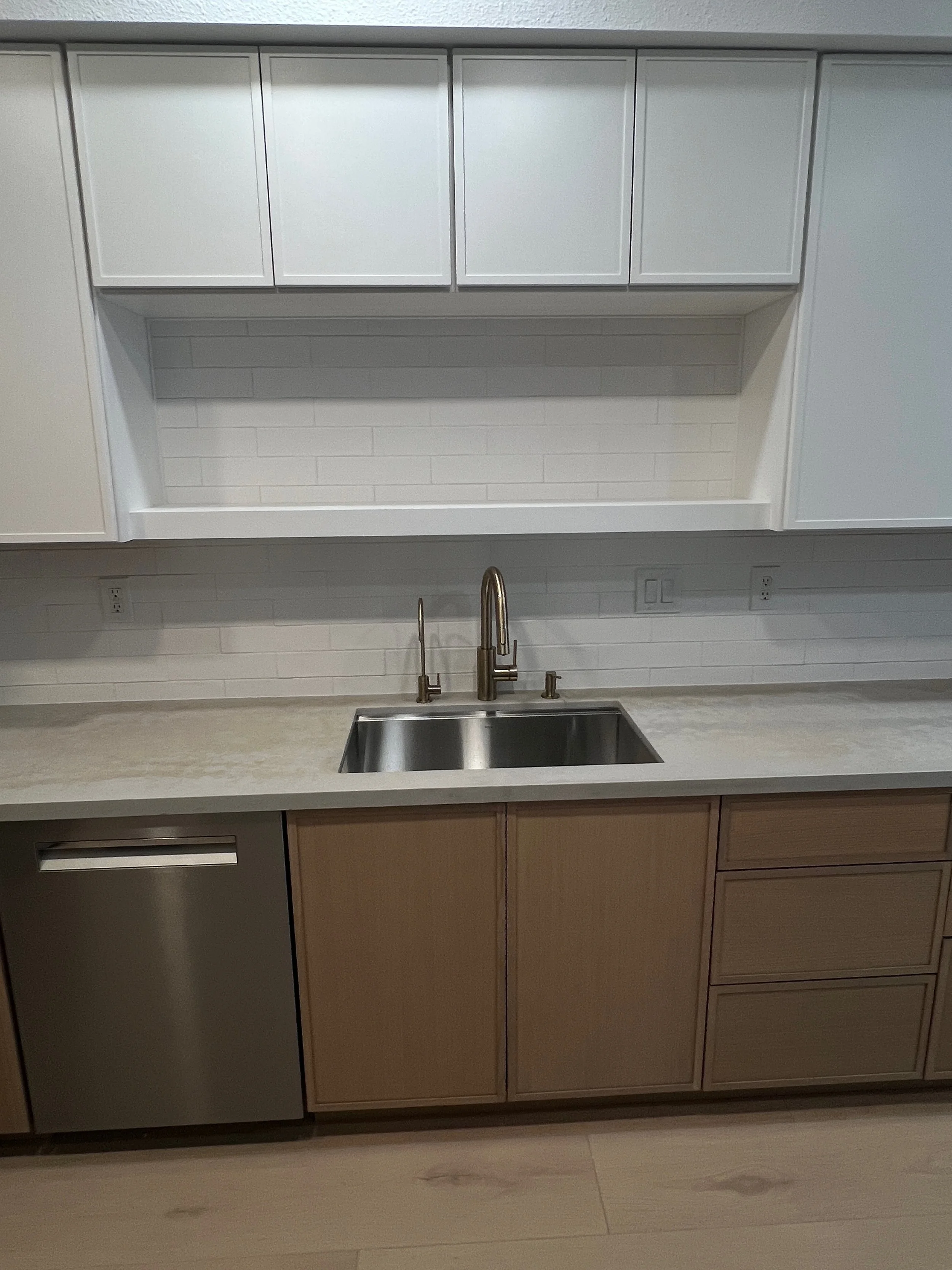 Kitchen with white upper cabinets, a beige lower cabinet, a stainless steel sink, and a brushed nickel faucet.