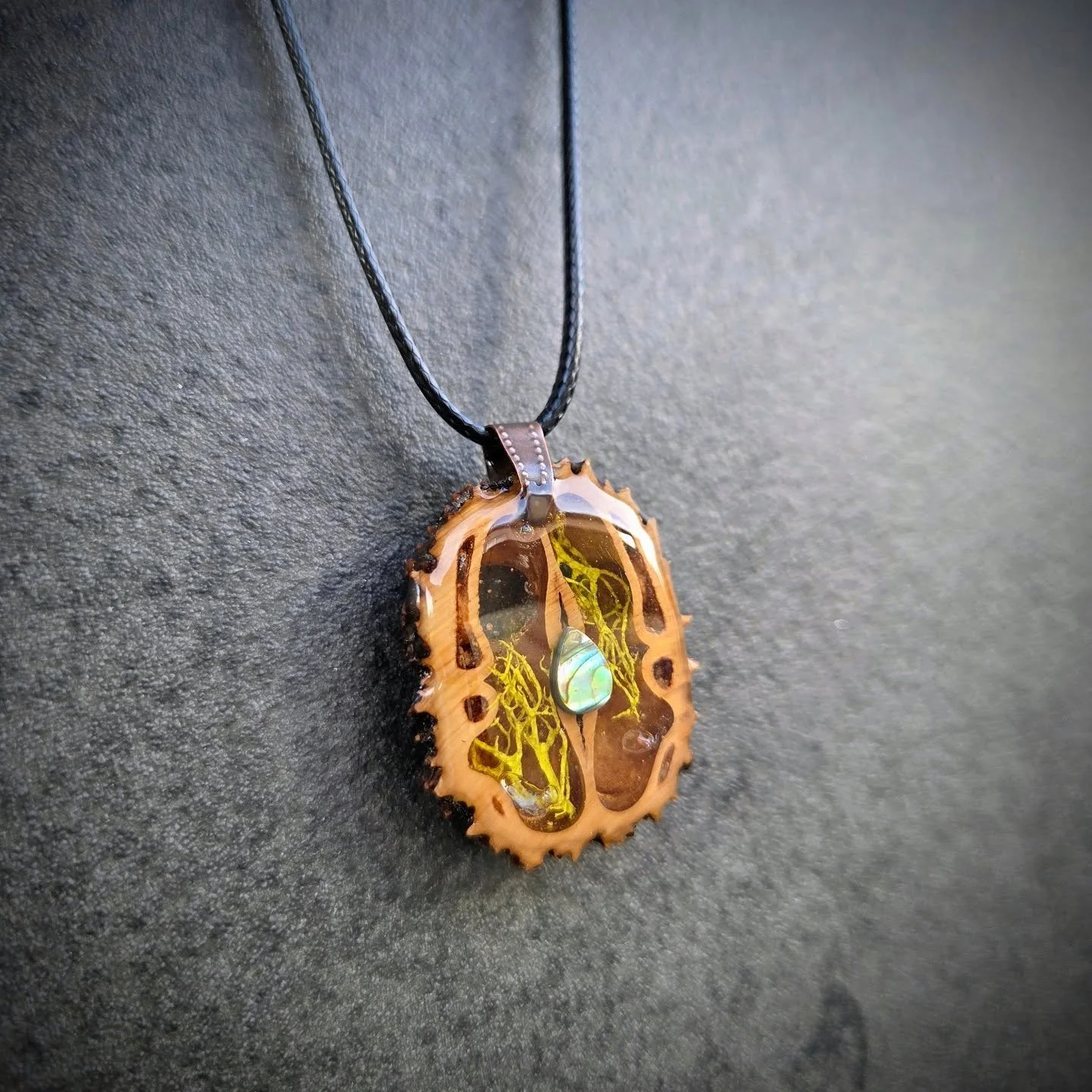 From forest floor to wearable art 🌿

This pendant started as a black walnut shell &mdash; shaped by nature, then carefully carved, filled with resin, and finished with an abalone drop that catches the light like a tiny piece of the ocean.

Each piec