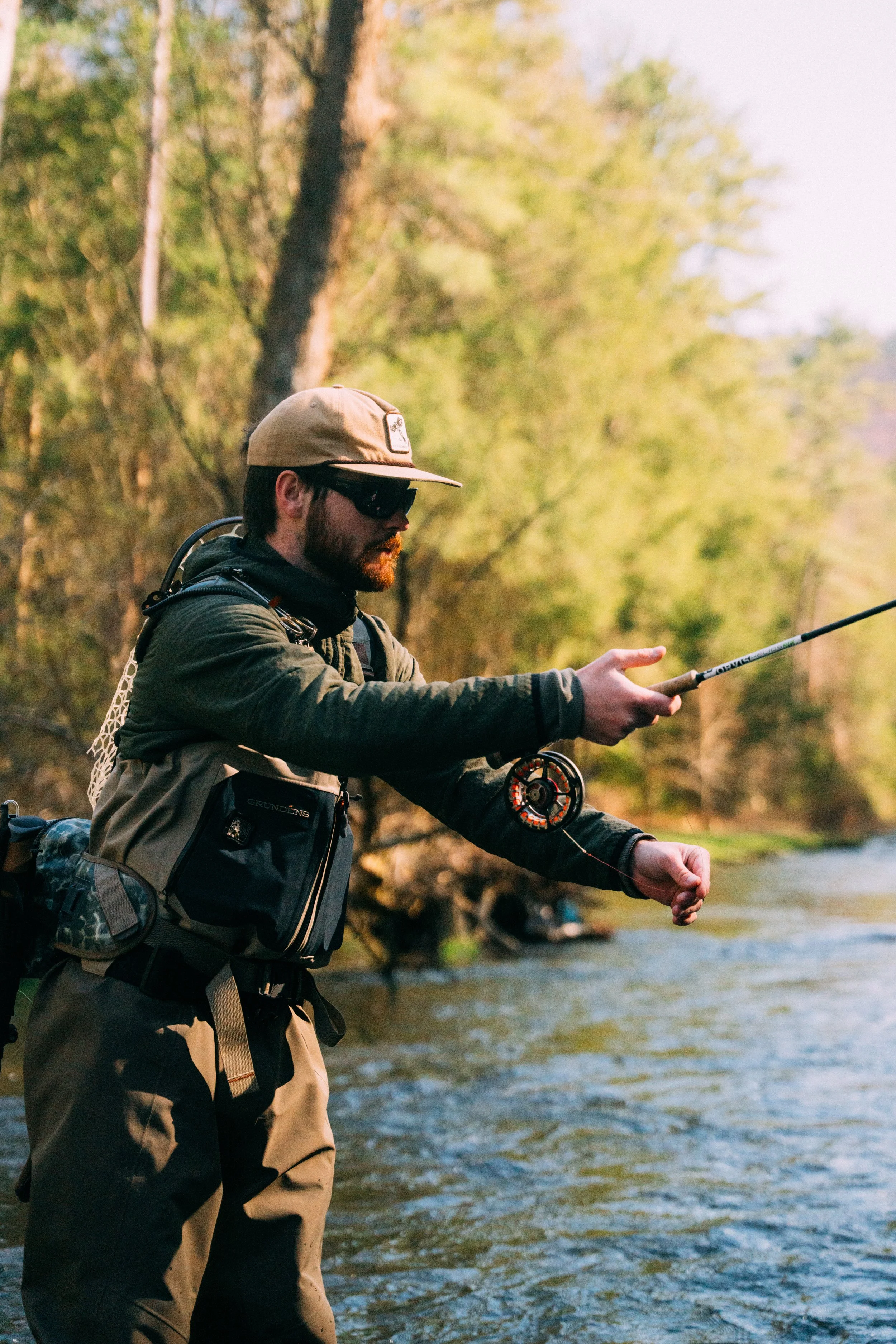 A man fishing in a river surrounded by trees.
