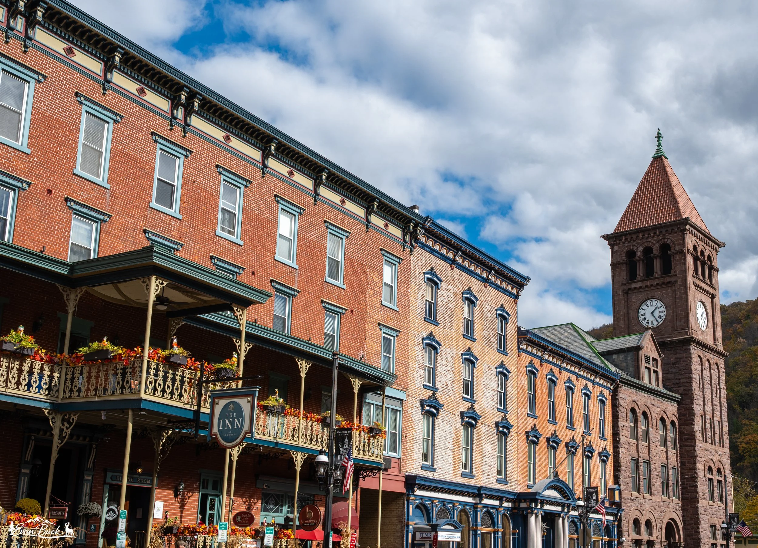 Historic brick building and clock tower in a small town with a blue sky and clouds in the background.