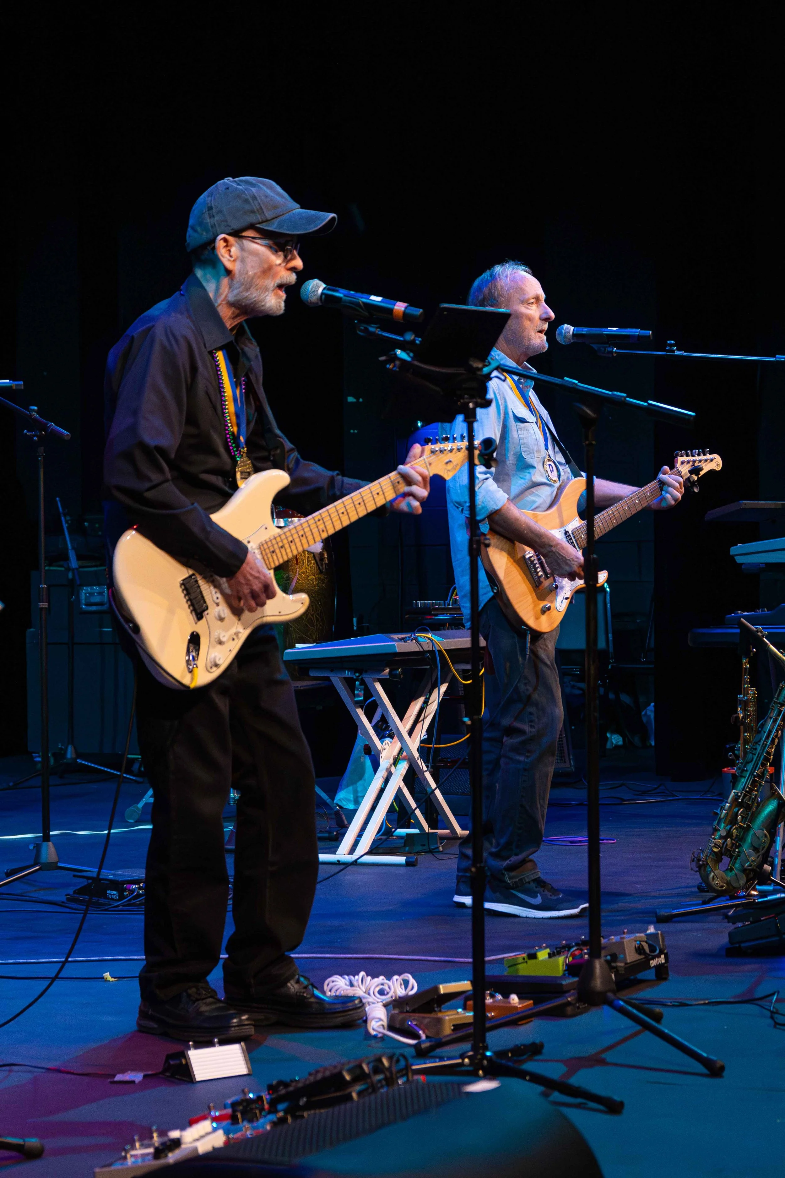 Two men playing electric guitars on stage during a live performance.