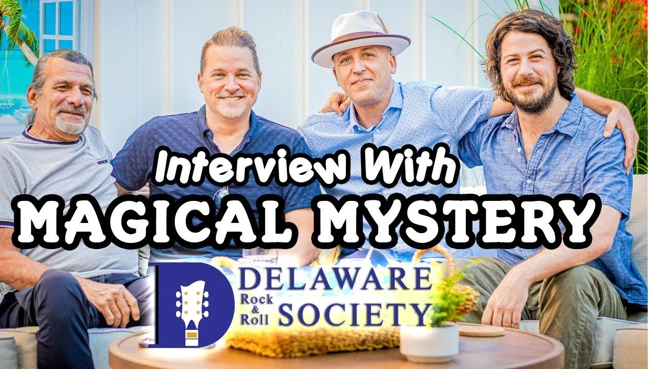 Four men sitting together on an outdoor couch, smiling, with text overlay that reads "Interview with Magical Mystery" and a logo for Delaware Rock & Roll Society.