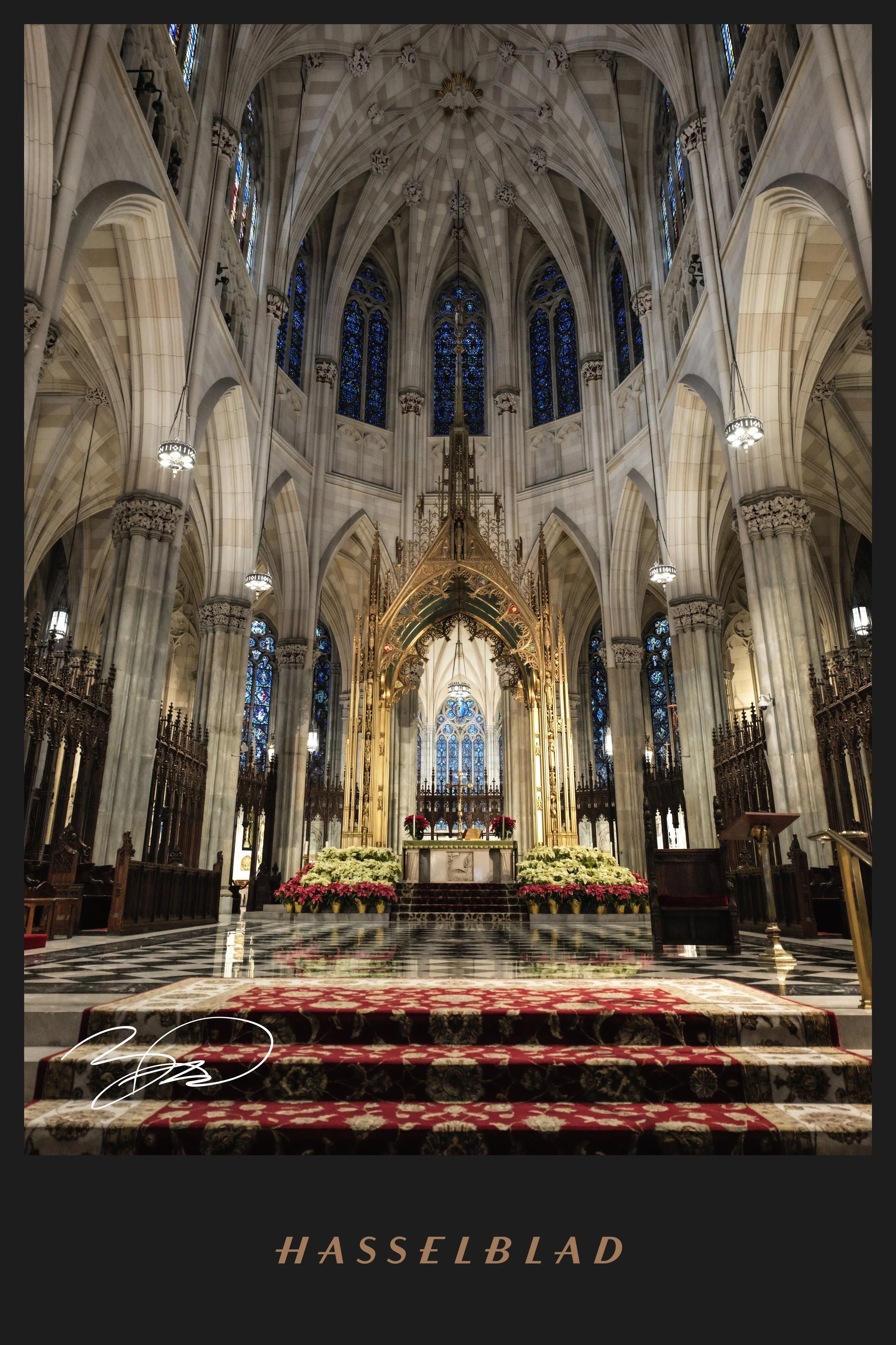 Interior of a Gothic-style cathedral with high vaulted ceilings, stained glass windows, and an ornate altar decorated with flowers and candles.