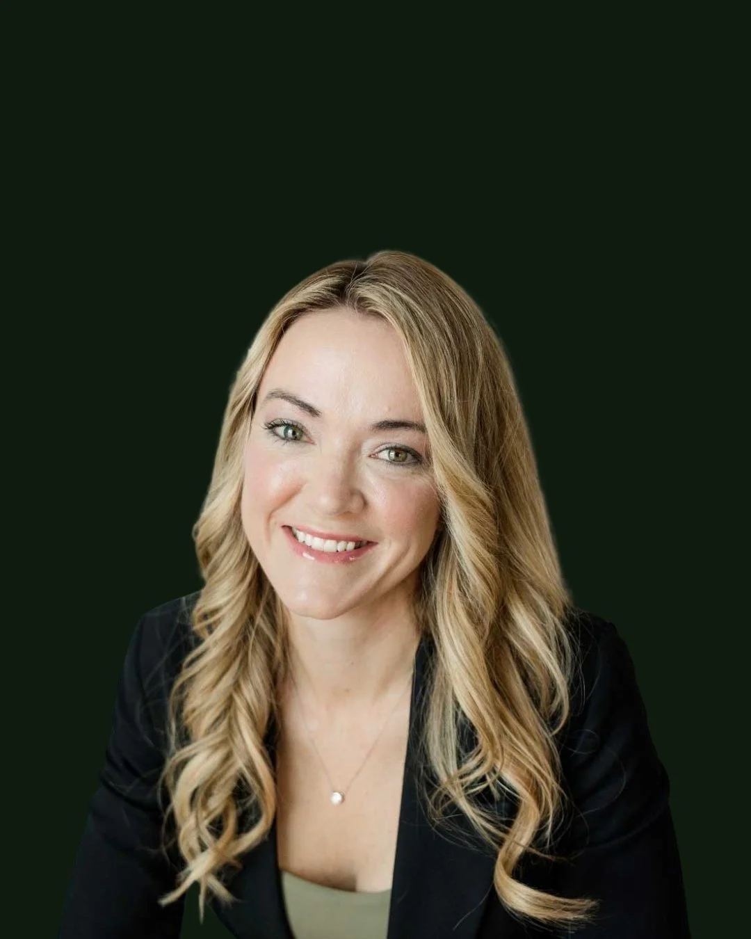 Headshot of a smiling woman with blonde wavy hair, wearing a black blazer and a necklace against a dark green background.