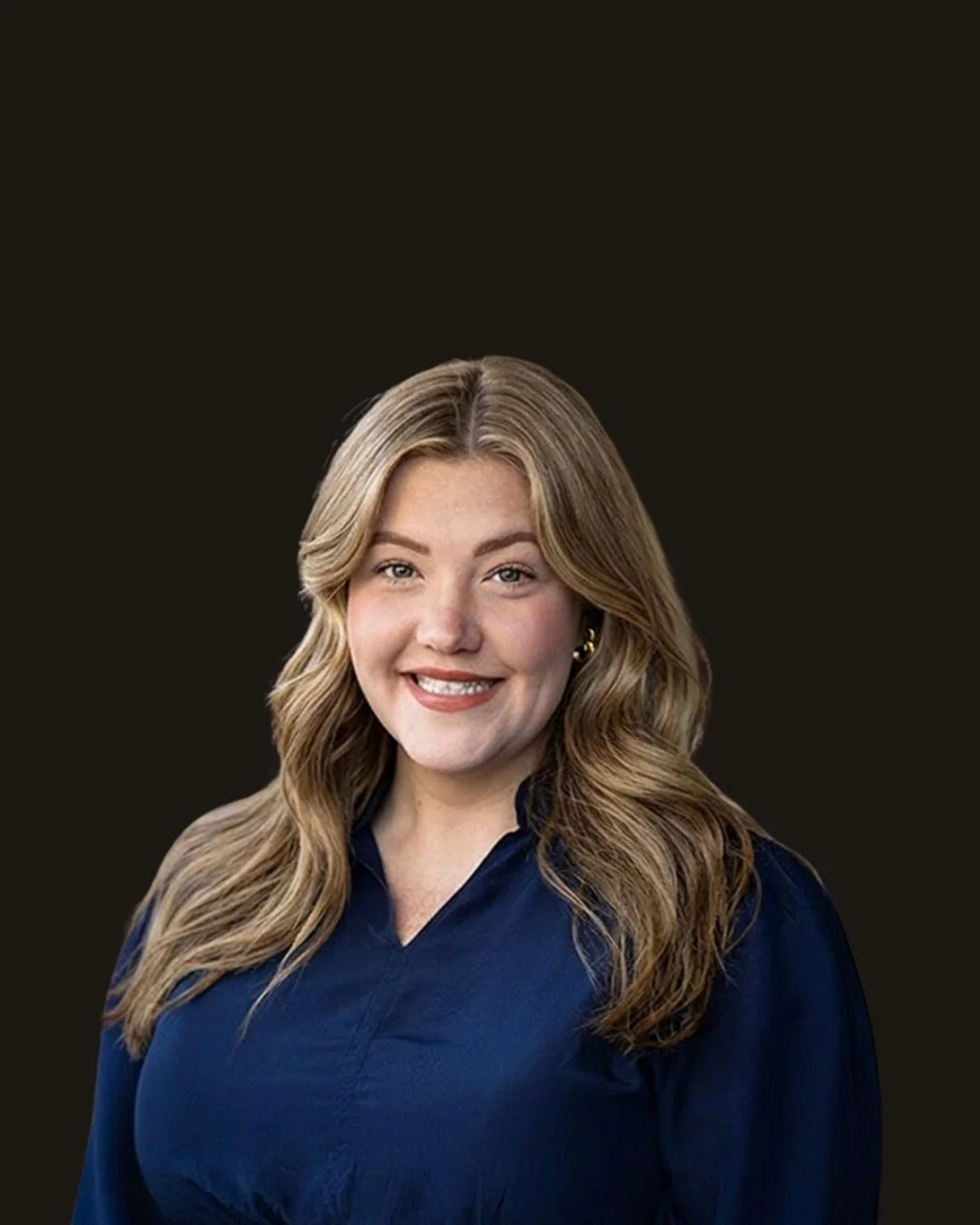 A woman with wavy blonde hair smiling, wearing a navy blue top, on a dark background.
