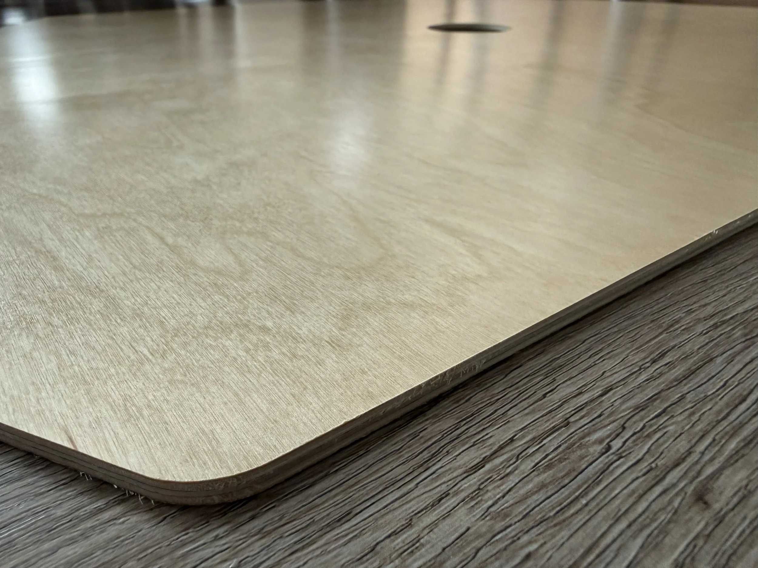 Close-up of a birch wooden trunk board with rounded edges and a darker wooden surface underneath.