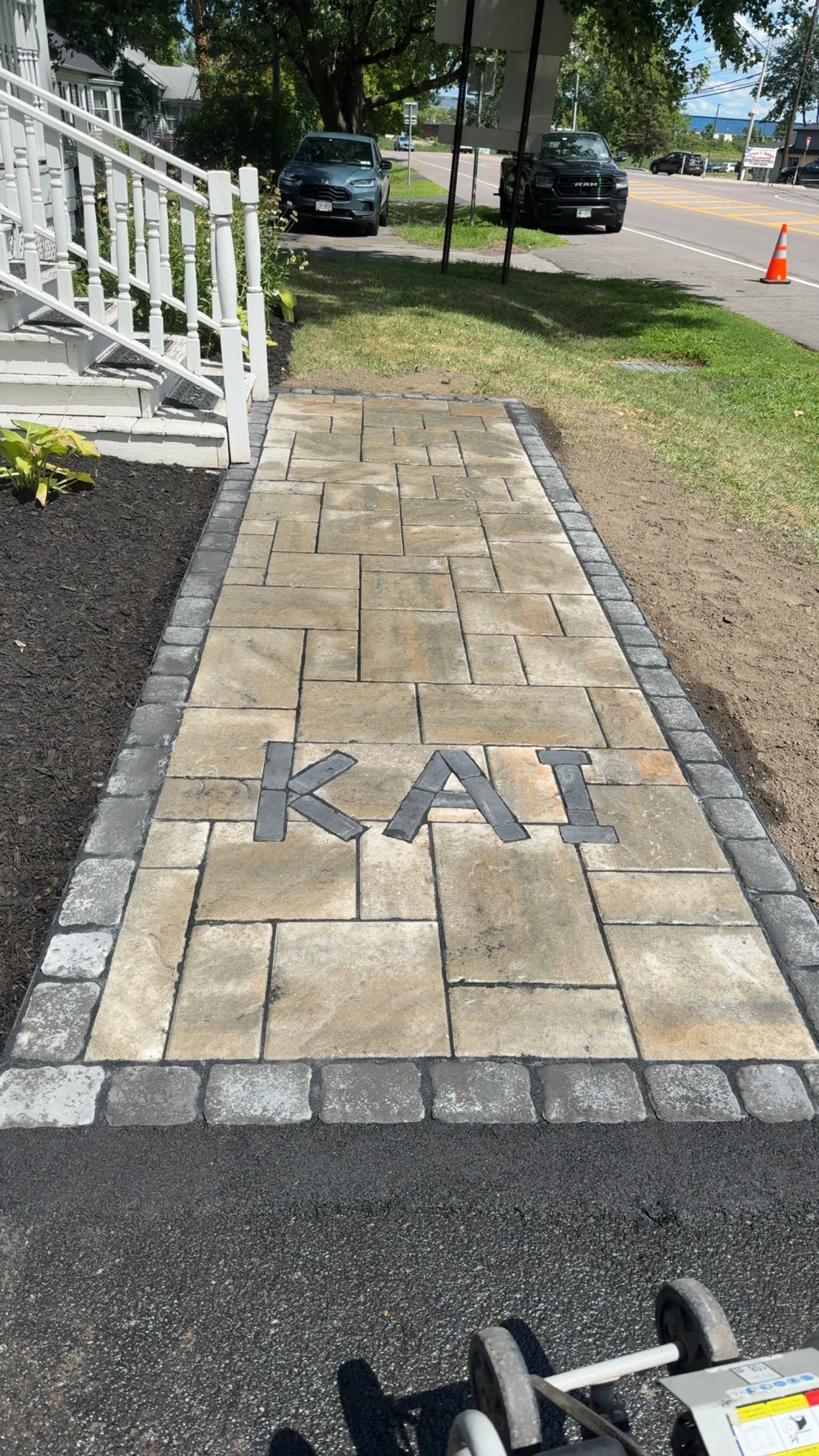 A paved sidewalk with the word 'KAI' in black stones near the bottom.