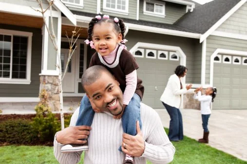 A young man sitting on a beige bench against a plain wall, wearing a gray polo shirt and cream-colored pants, with a serious expression.
