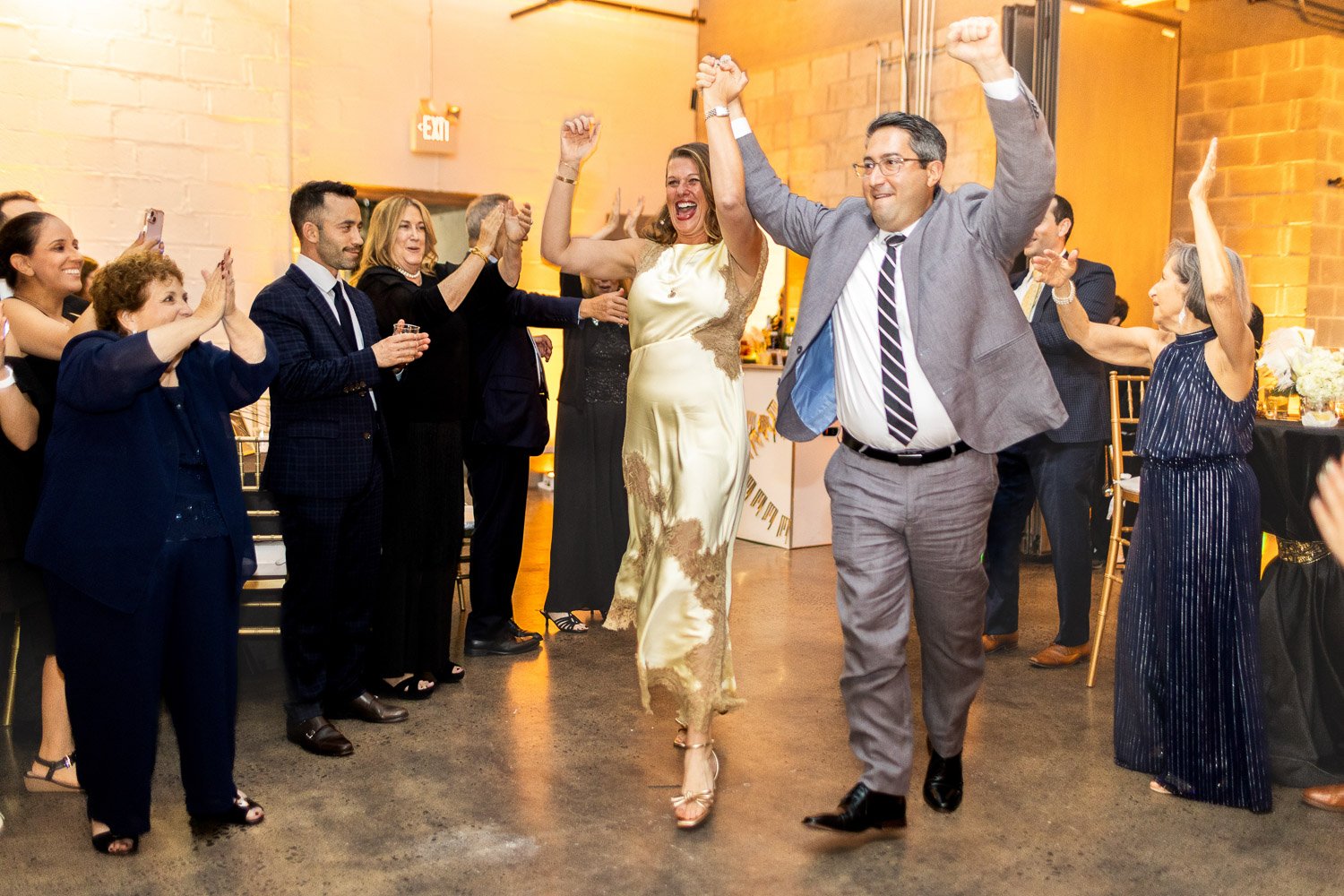 People celebrating at a Bat Mitzvah with a couple dancing in the center, surrounded by friends and family clapping and cheering.
