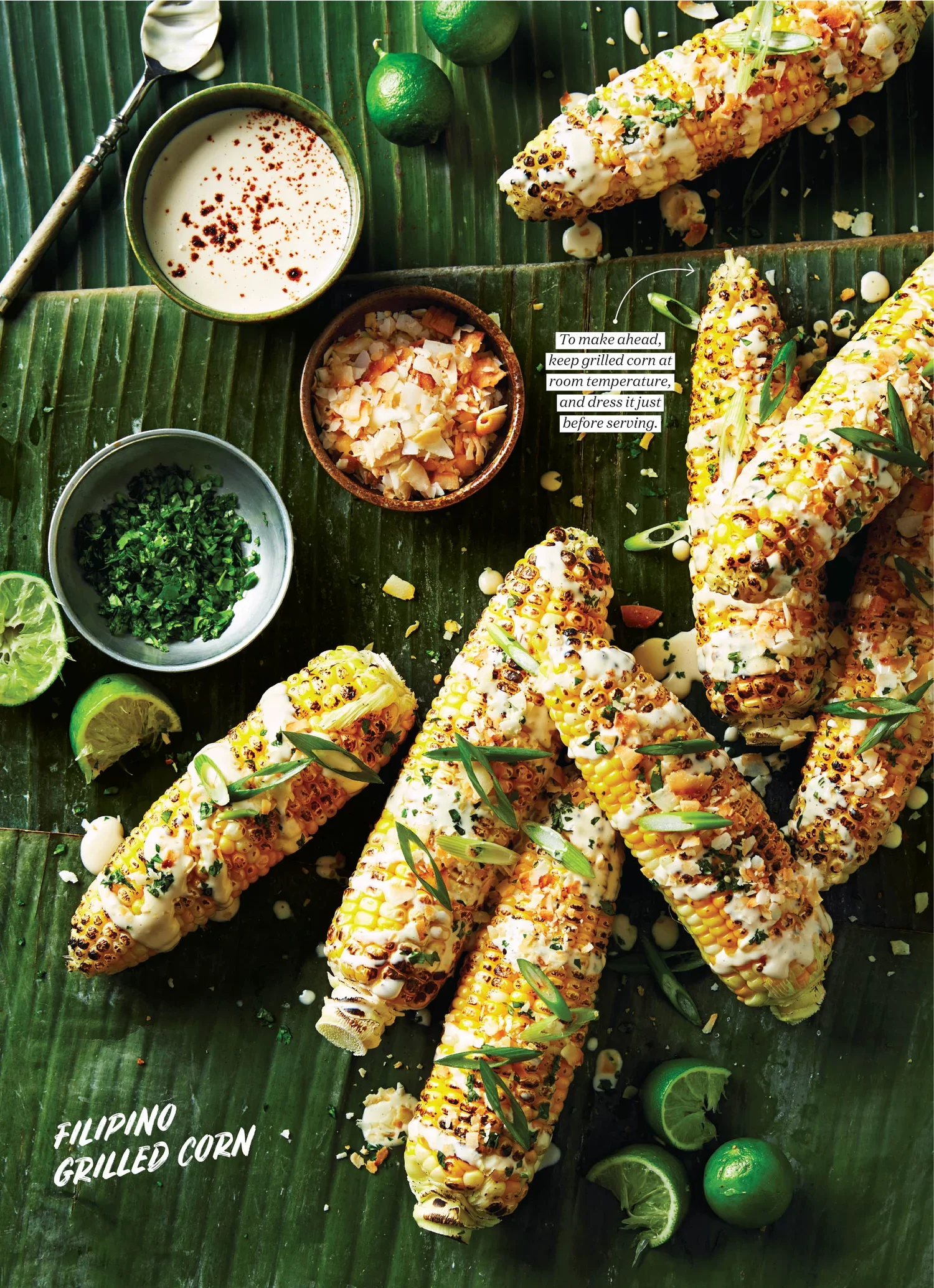 Chatelaine Magazine, styled by rayna marlee. Grilled Filipino corn on the cob garnished with herbs and served on a banana leaf, accompanied by lime wedges, a small bowl of chopped cheese, a bowl of butter, and a cup of creamy sauce.