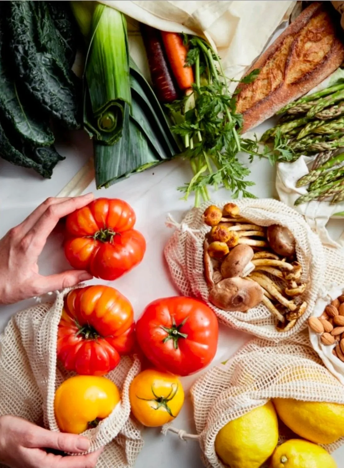 Cover of a cookbook titled "Eat Good Fat" art direction and prop styled by rayna marlee. Fresh vegetables including green zucchinis, leafy greens, carrots, asparagus, tomatoes, yellow lemons, and a basket of mushrooms on a white surface.